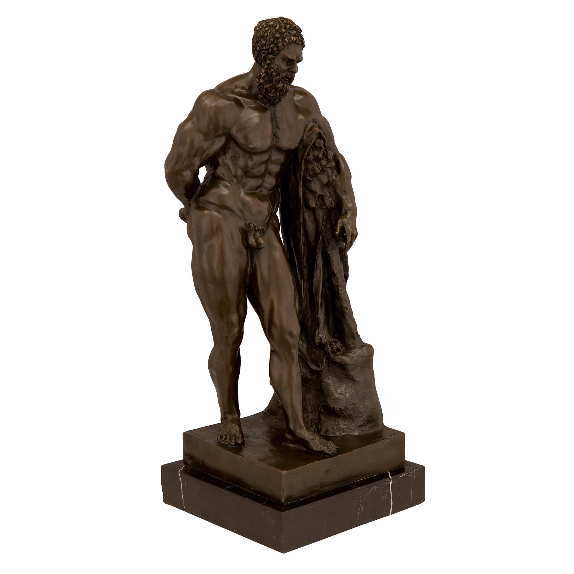 An impressive patinated bronze statue of Hercules. The statue is raised by a square Black Antique marble base. Above is the handsome patinated bronze Hercules leaning on what is likely the skin of the Nemean lion he was tasked to kill by the king.