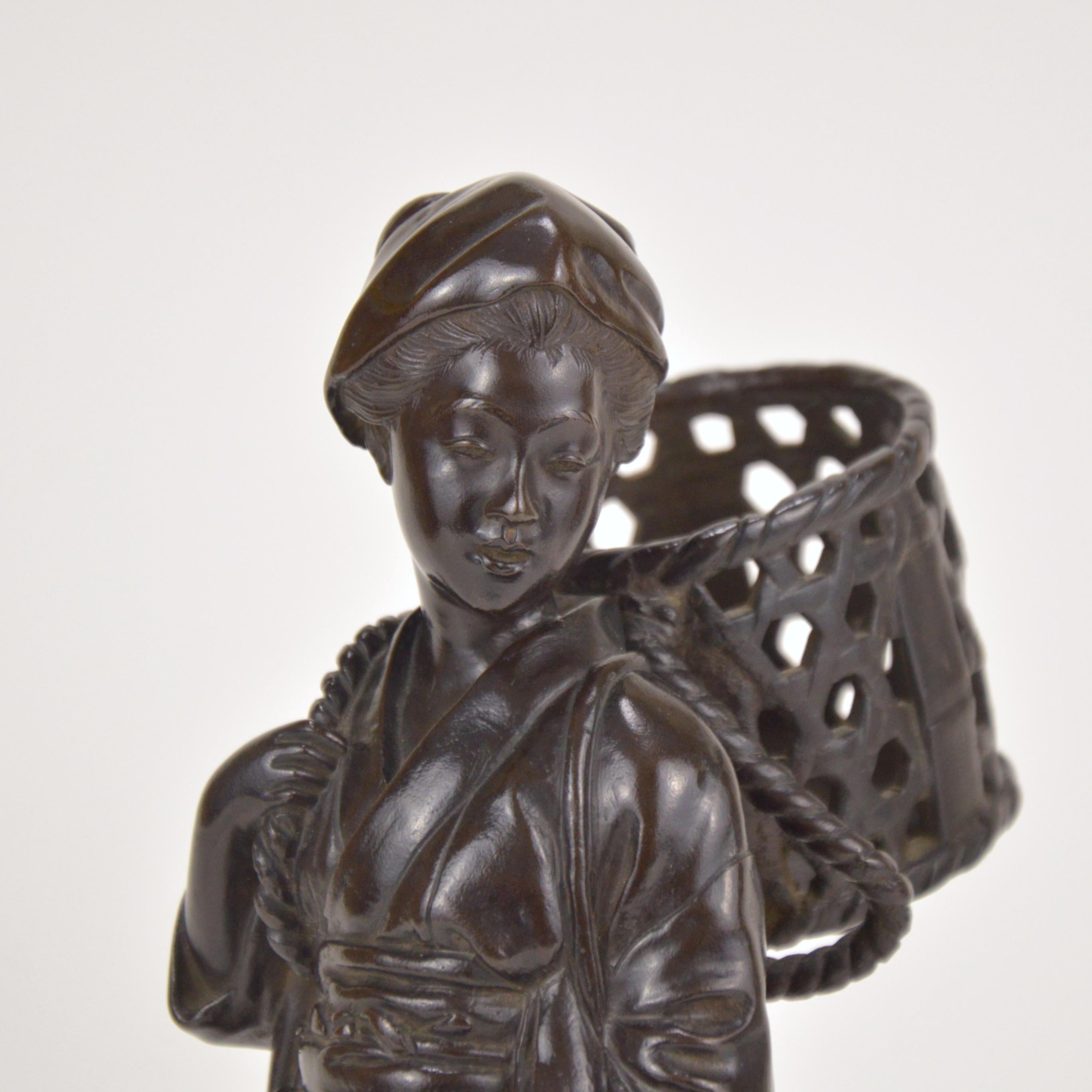 Patinated bronze statue representing a young peasant girl holding a basket. Japan, early 20th century. Marked on the base.
