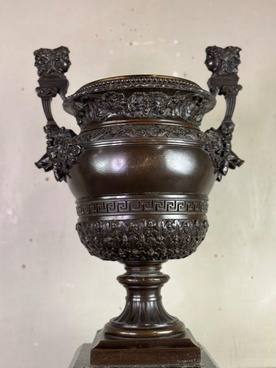 Patinated bronze vase with handles topped with two-headed busts. Reduction of a vase forming part of the decoration of the North Parterre of the Palace of Versailles. Made in 1665 after the designs of the royal goldsmith Claude I Ballin. signature
