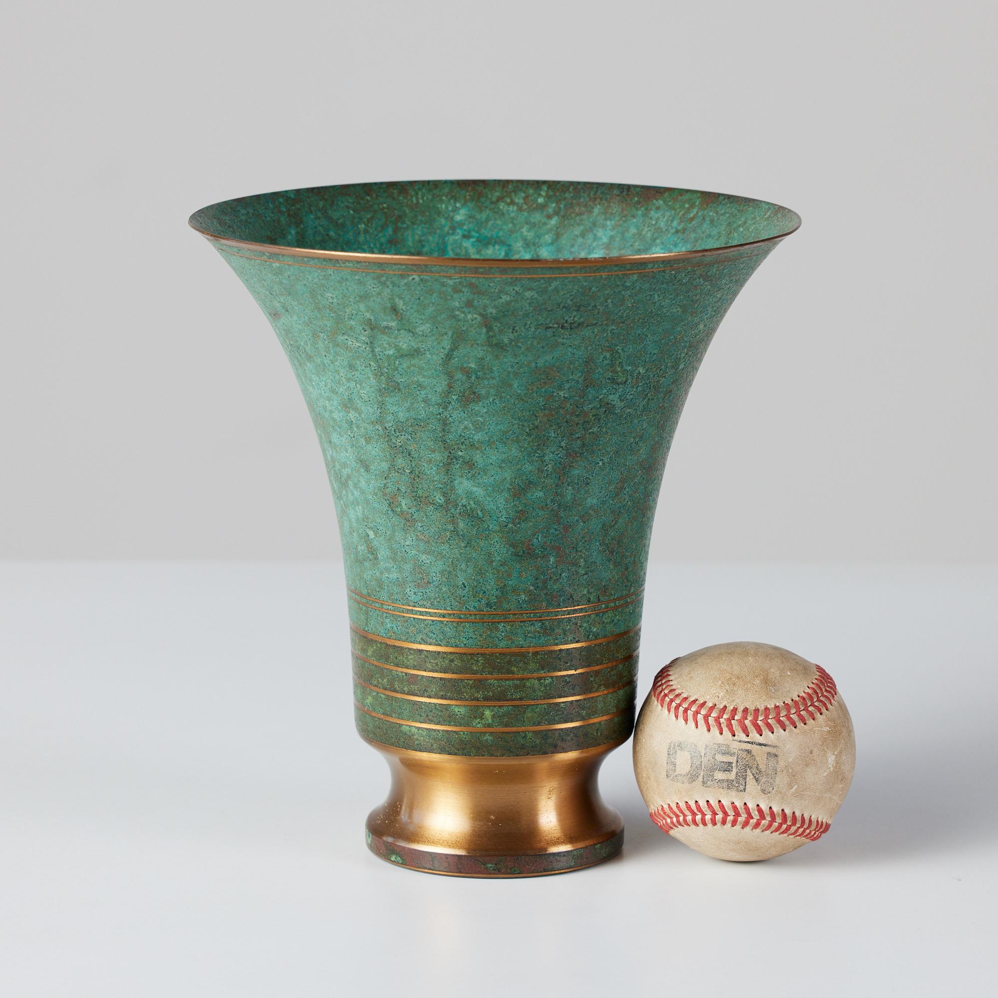 This patinated Art Deco bronze tulip shaped vessel by Carl Sorensen, c.1930s, USA flares out at the top with a con-caved polished foot. The base of the vessel features clean polished bronze lines, creating a lovely contrast between the verdigris and