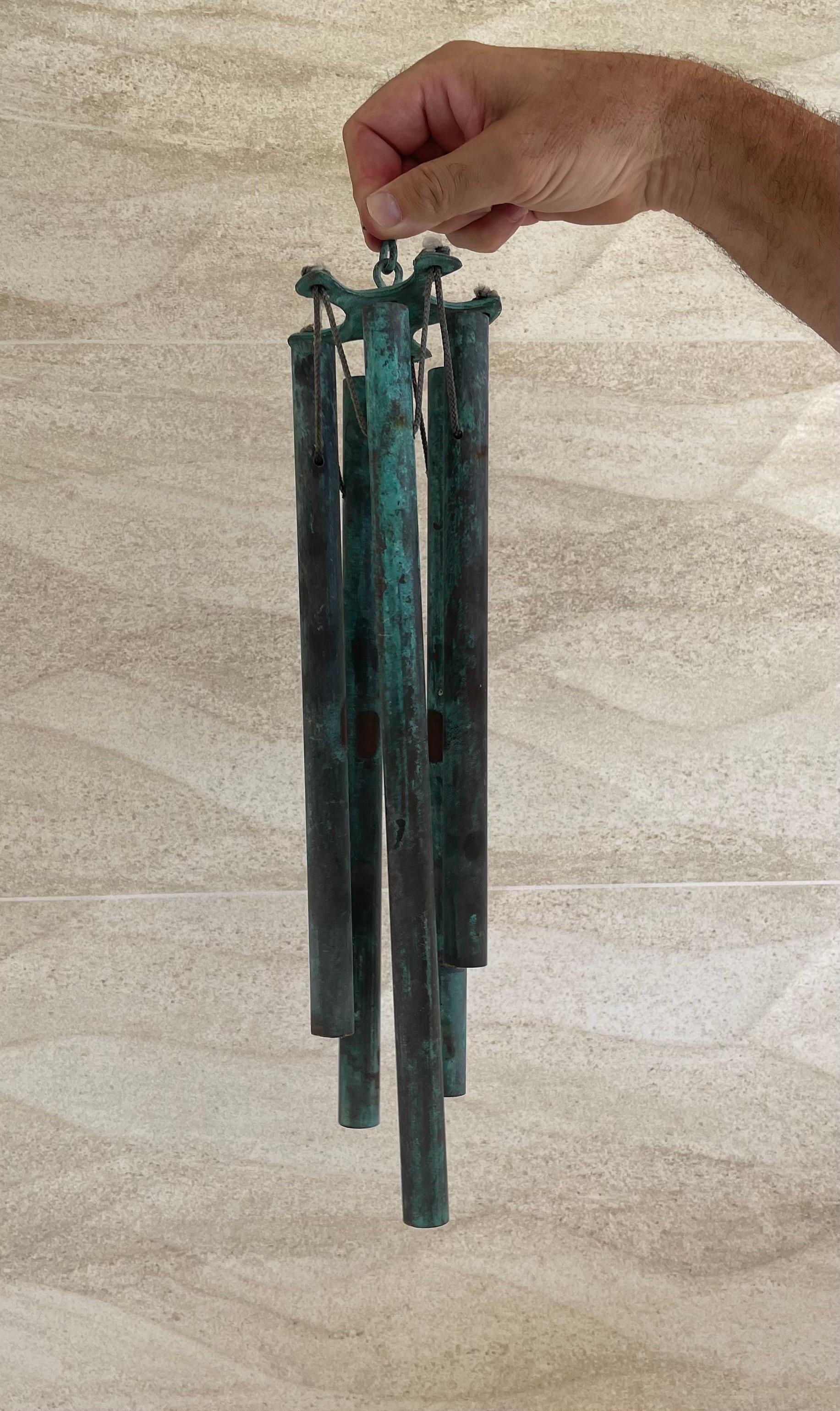 A wonderful set of patinated bronze wind chimes in the style of Walter Lamb, circa 1950s. This set features five patinated bronze tubes attached to a star shaped top with nylon rope. The chimes are in good vintage condition with a gorgeous verdigris