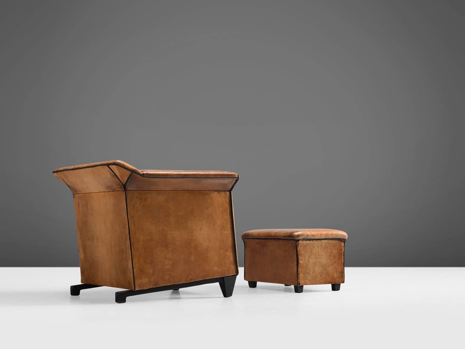 Cognac leather club chair with matching ottoman, Europe, 1960s.

Patinated club chair with matching ottoman in cognac leather. The sturdy design has an interesting base that gives the model certain lightness. The hefty shape of these comfortable