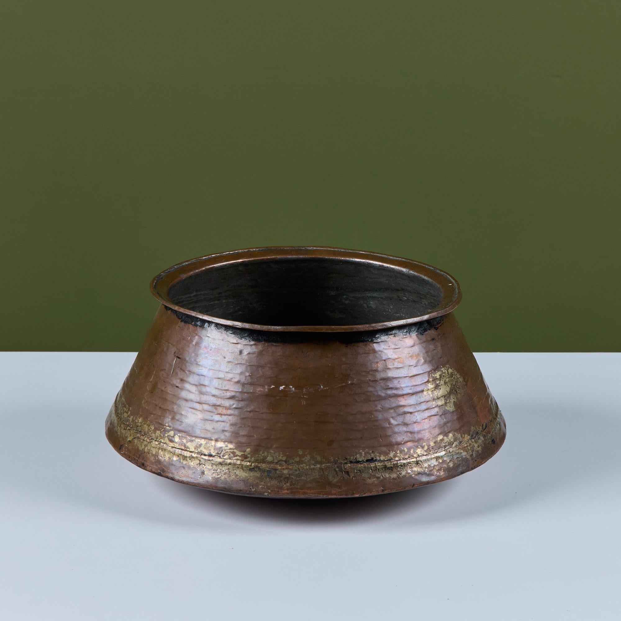 Bol ou handi en cuivre martelé à fond arrondi. L'intérieur de cette pièce est en acier tandis que l'extérieur présente une patine de cuivre, ce qui en fait une jardinière ou un bol décoratif unique.

Dimensions
14