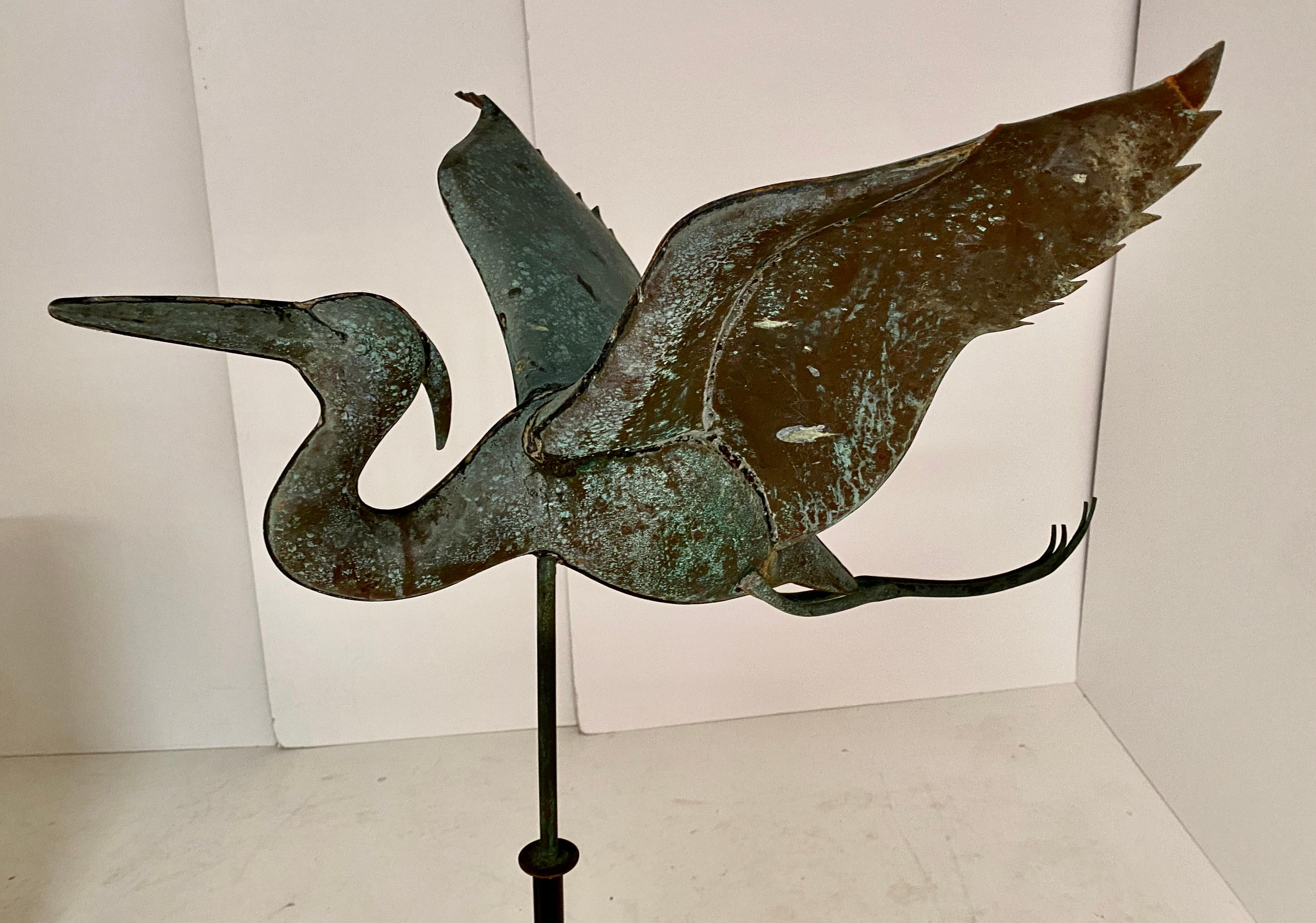 Well crafted heron weathervane in copper. Wonderful natural patina. Unusual subject: spread wing heron with trailing legs, just as in nature. Fitted into a painted metal stand.