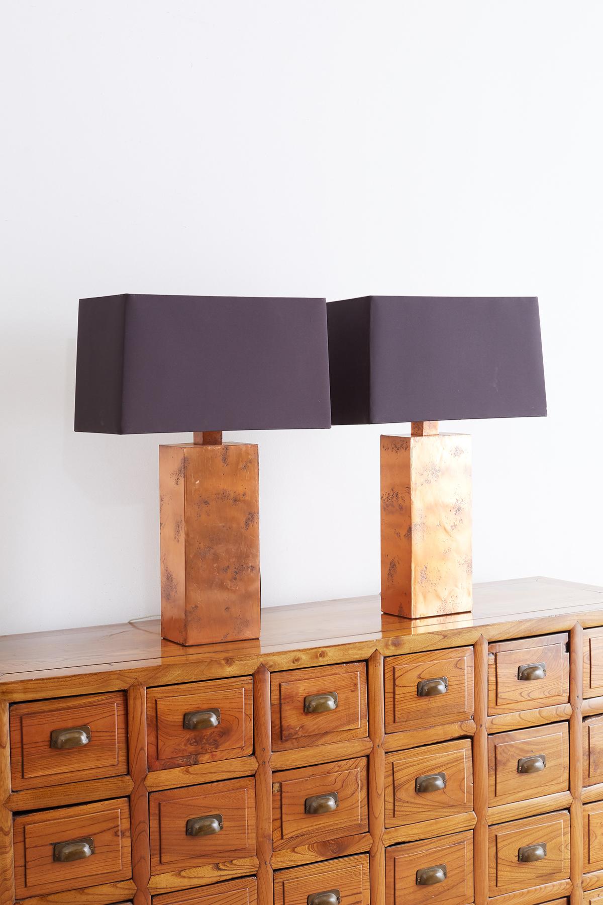 Stunning pair of table lamps by Arteriors Tanner Kenzie line of lighting. Features rectangular forms covered with copper having a lovely patinated metal patina. Includes original black fabric shades with a gilt interior. Unique modern style with a