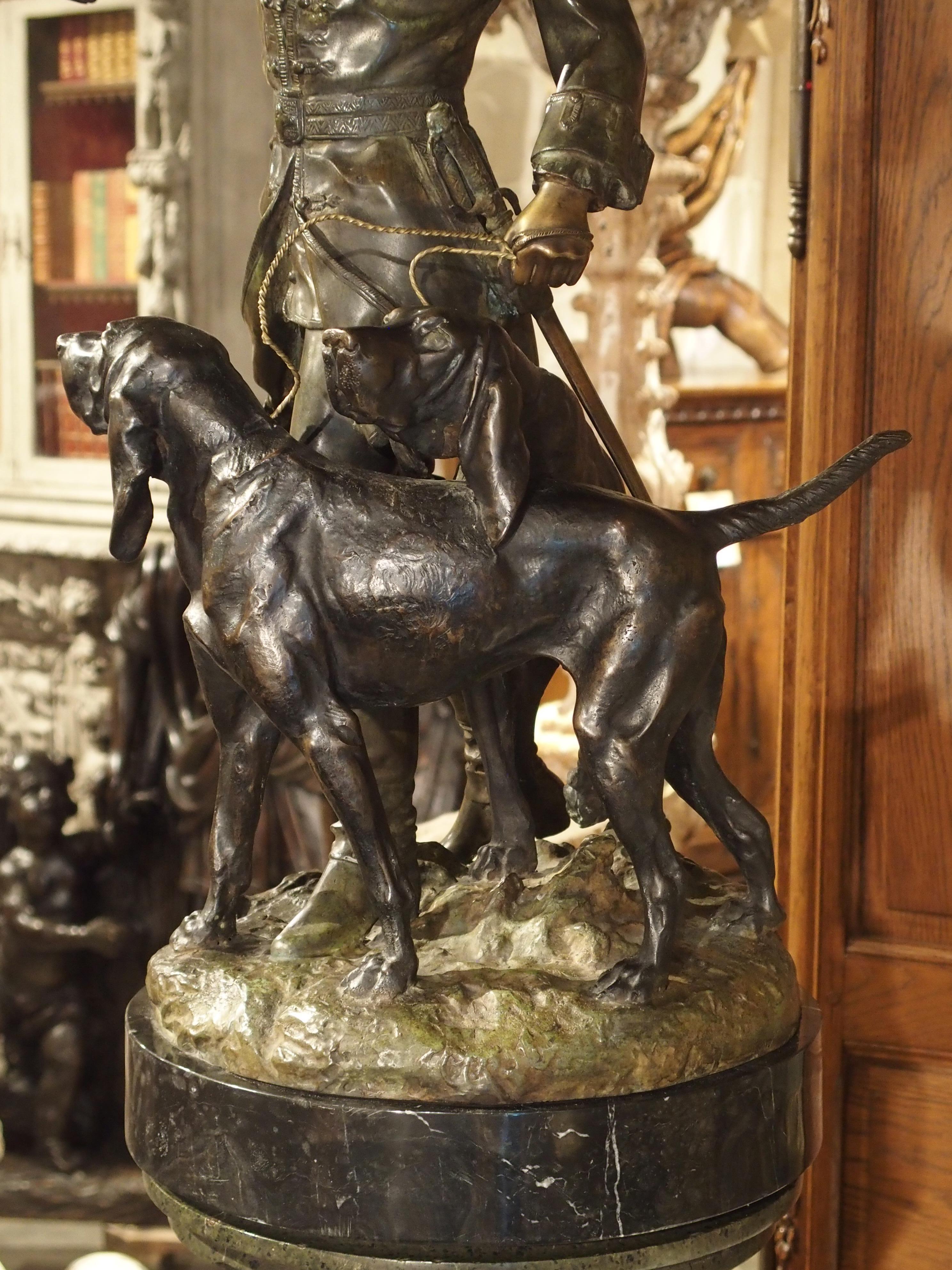 Bronze Statue française en bronze patiné représentant un chasseur et des chiens de chasse sur un piédestal en marbre