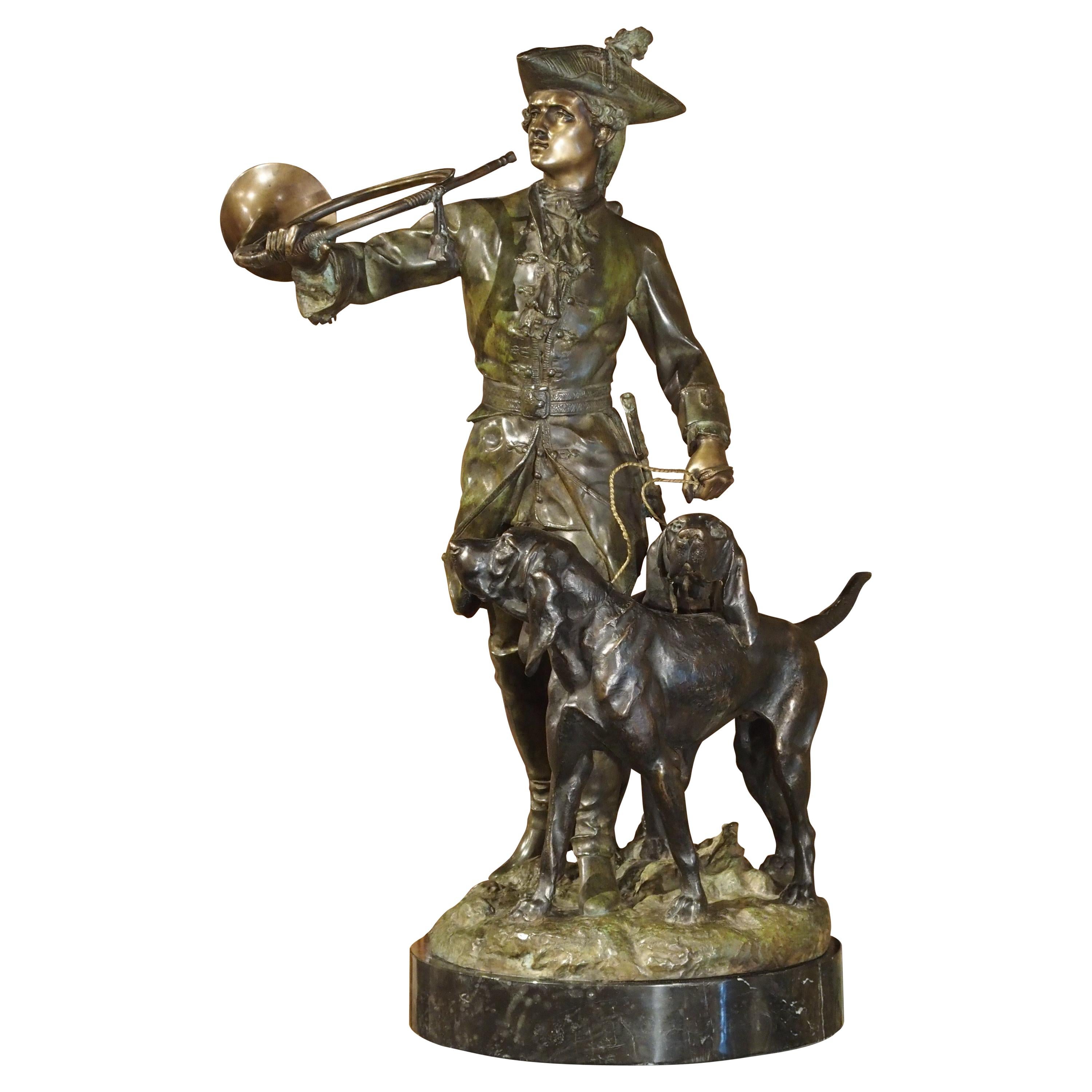 Statue française en bronze patiné représentant un chasseur et des chiens de chasse sur un piédestal en marbre