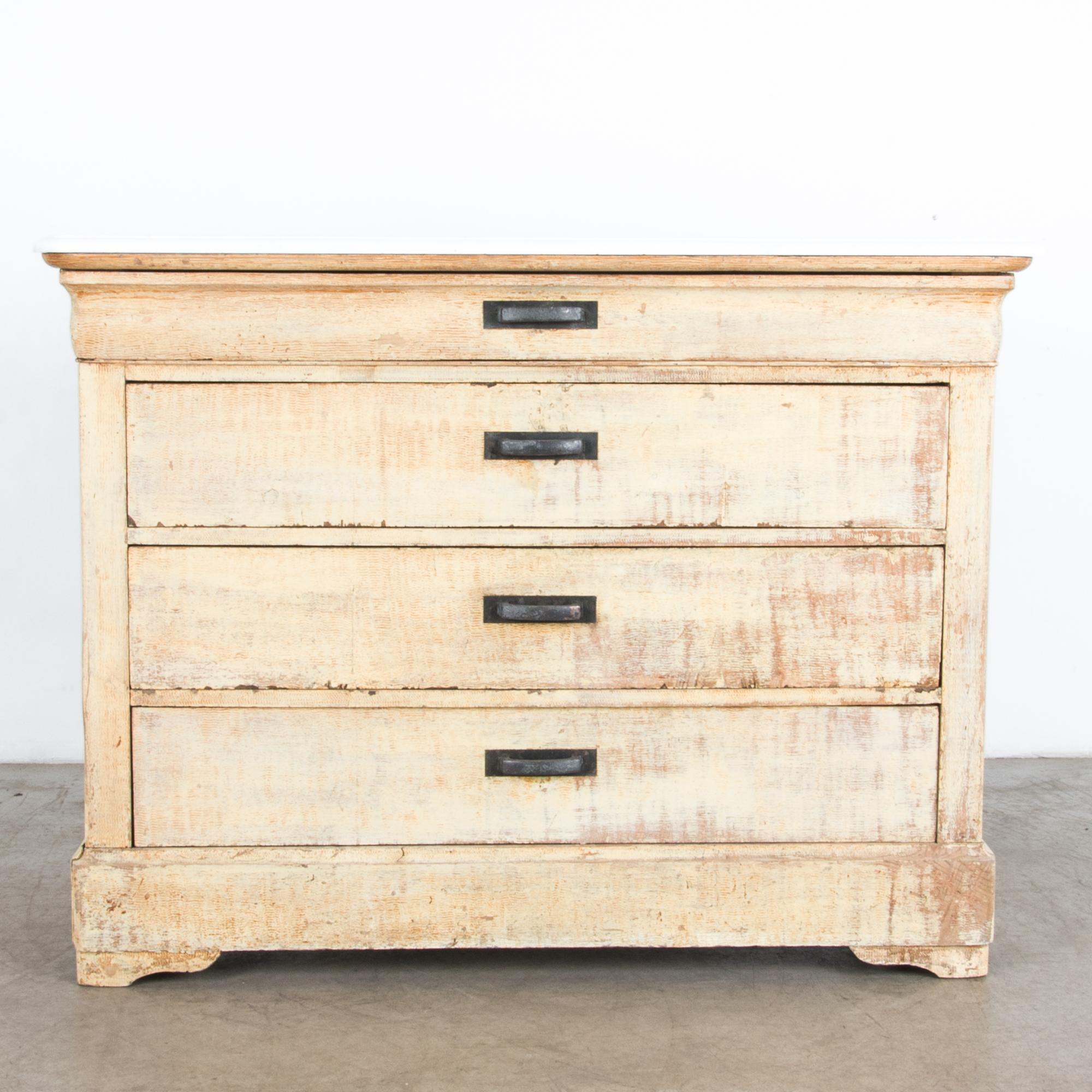 A sleek and simple chest of drawers from France circa 1880 in oak, with a unique textured patina and a white and grey marble top. A four drawer design blends with the distinctive Louis Phillipe shape, with a thick base moulding and feet, the top