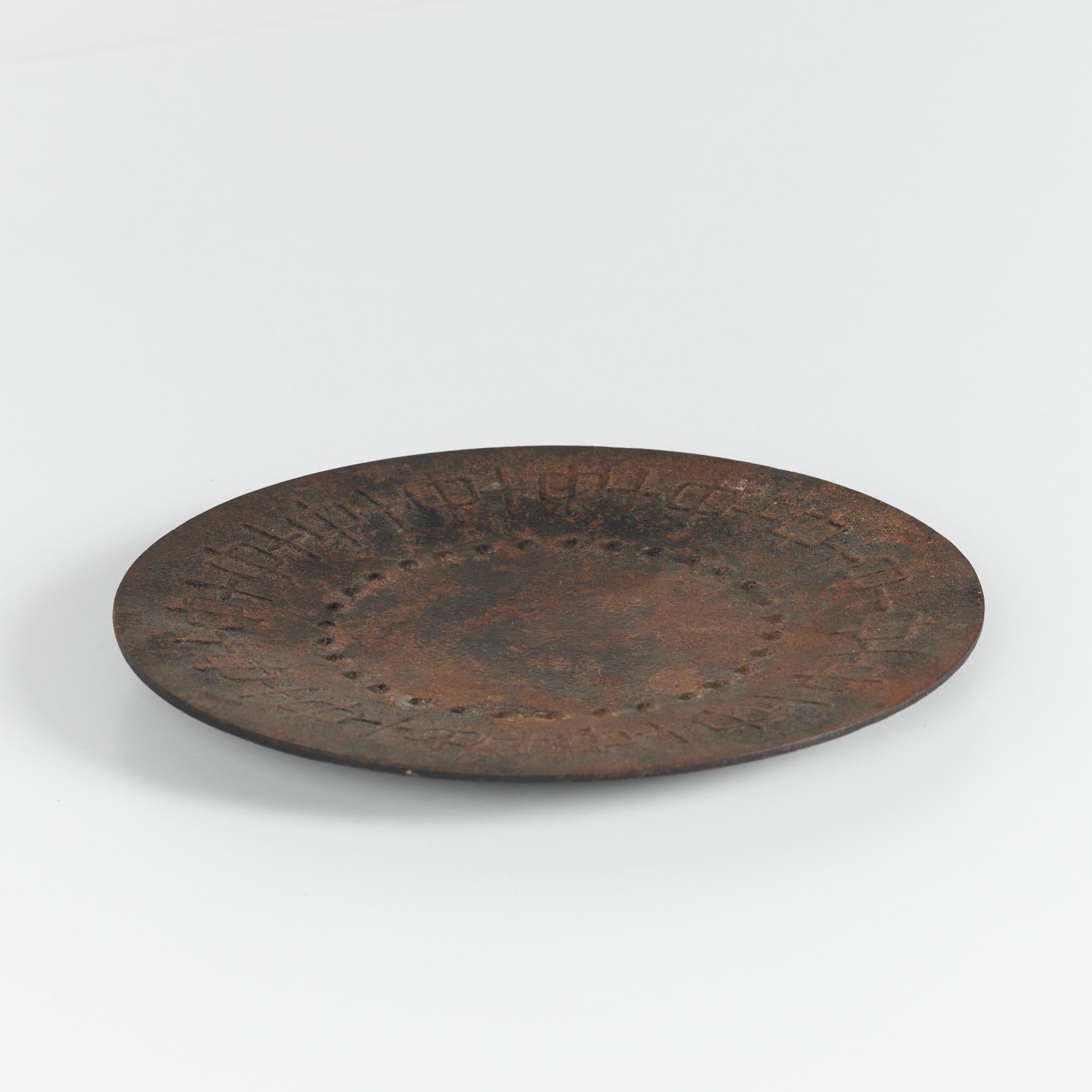 Round patinated metal plate with a unique raised linear detailing.

Dimensions: 9.5