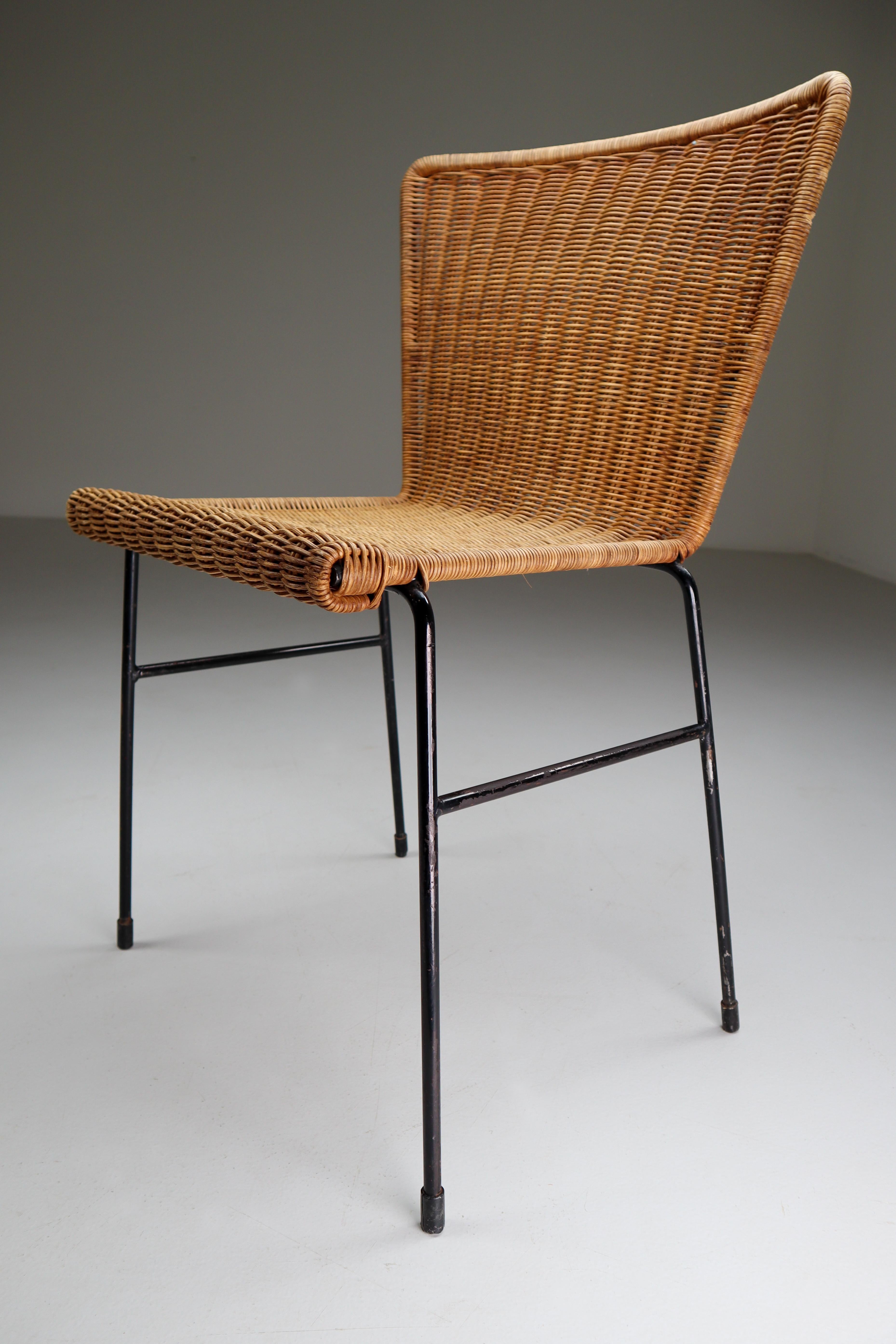 Patinated woven wicker midcentury chairs designed and produced in The Netherlands during the 1950s. The chair is made from handwoven wicker for the seat and he frame is made of black lacquered steel. They are comfortable to sit in and create an
