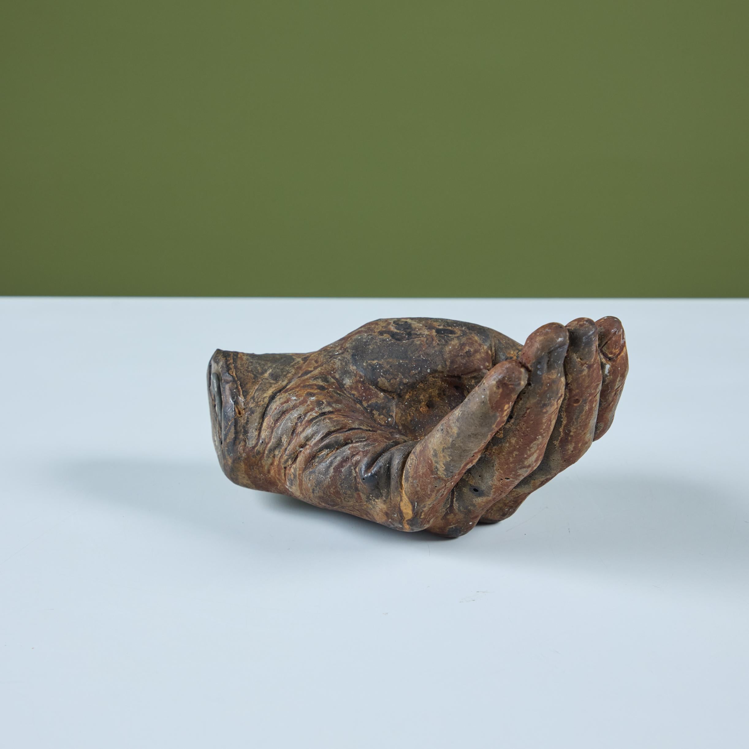 Mano de metal fundido al estilo de Pietrina Checcacci. La mano de metal macizo presenta detalles de nudillos y uñas. Se puede utilizar como pisapapeles, decoración escultórica o portavelas, ya que esta pieza tiene una hendidura redonda en la