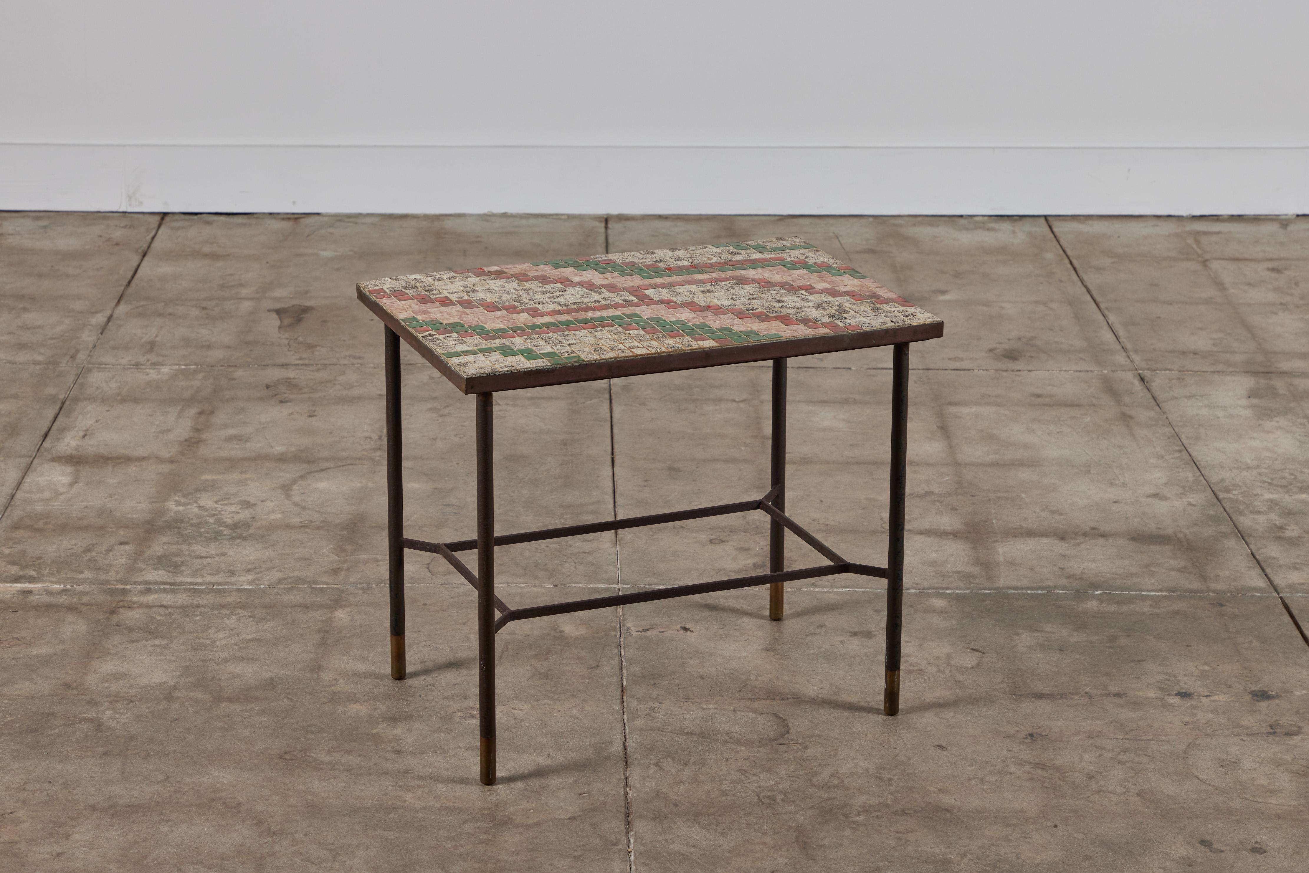 Patinated metal side table features a four legged patinated steel frame with square tiles inlaid to the table top in a geometric pattern. The tiles feature colors of red and pink tones, green and earth tones. 

Dimensions
24.25” width x 24.25”