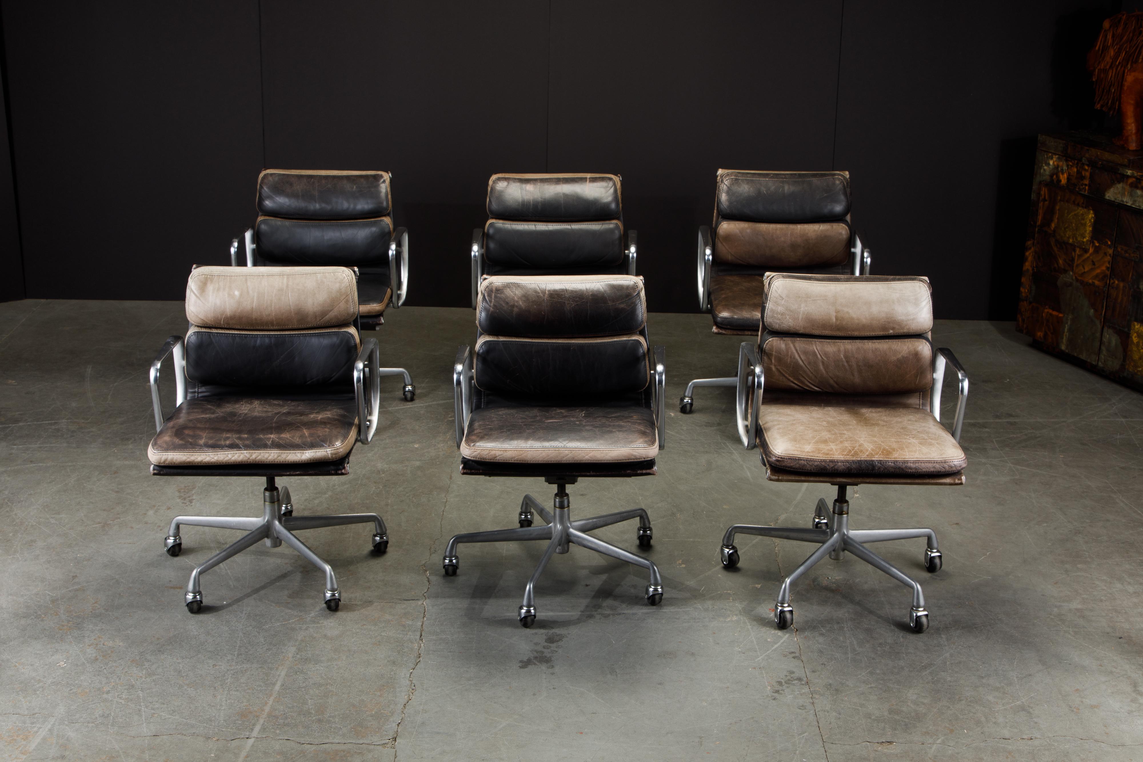 This set of six (priced individually) sought after and in-demand patinated leather desk chairs are the classic 'Soft Pad Management Chair' from the aluminum group line, designed by Charles and Ray Eames for Herman Miller. Featuring their original