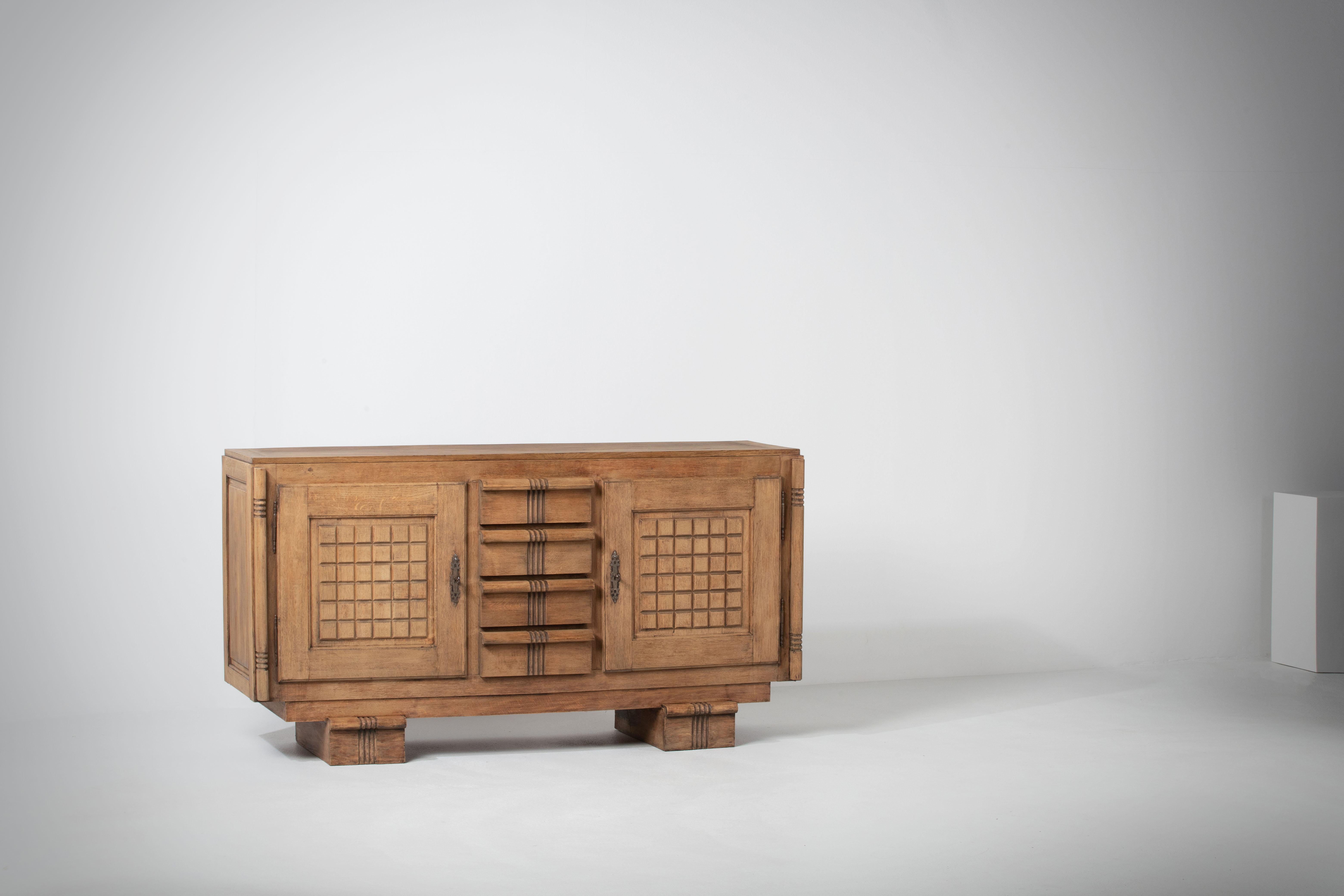 Large Credenza, solid oak, France, reminiscent of the work of Charles Dudouyt, 1940s.
Large Art Deco Brutalist sideboard. 
The credenza consists of two storage facilities and covered with very detailed designed doors, in the center, drawers.
The
