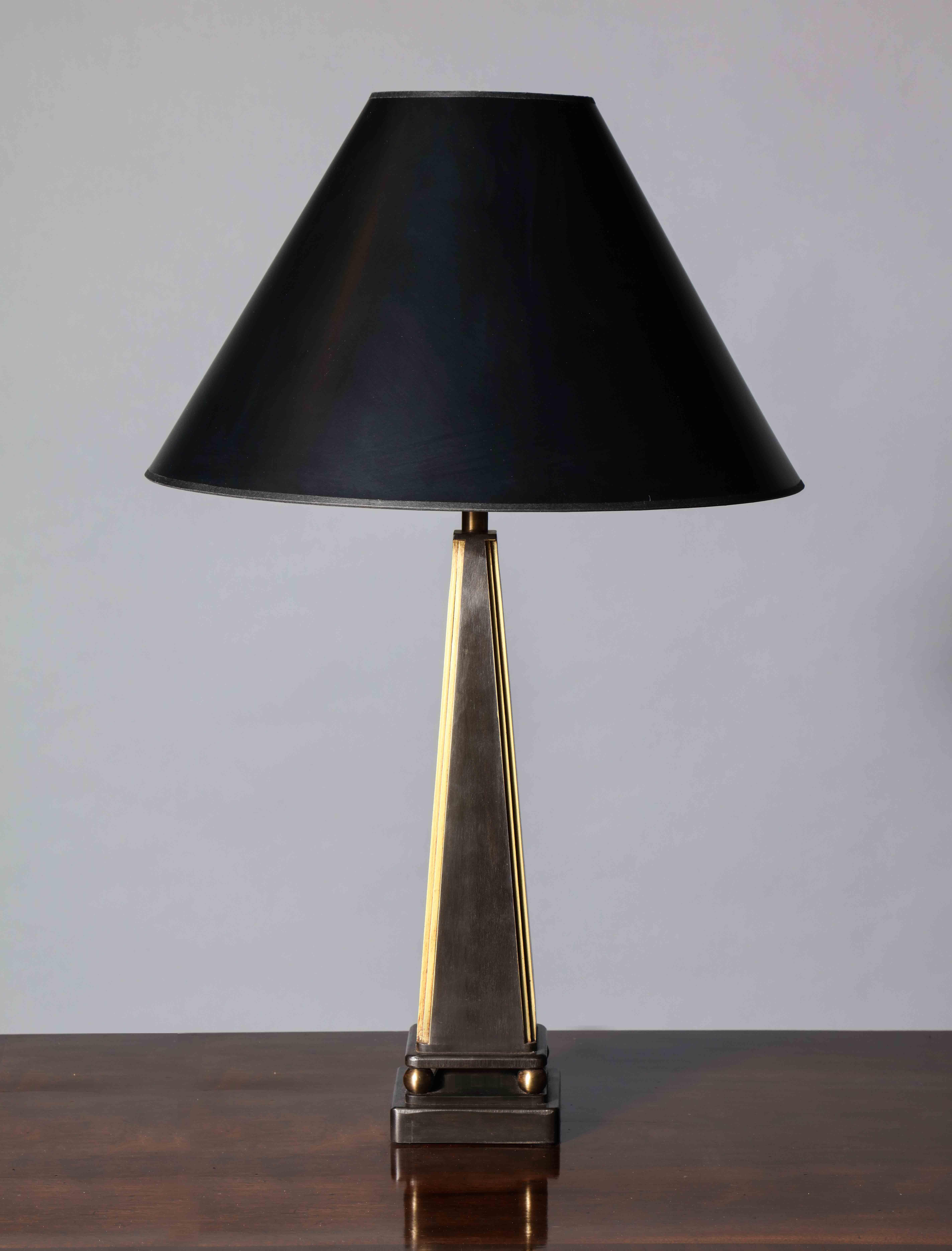 A handmade steel table lamp in pyramid form – raised on ball feet and set on a square plinth. The design references the French neoclassical aesthetic of the 1930s through late 1940s.

The brass detailing has been lightly antiqued while the main