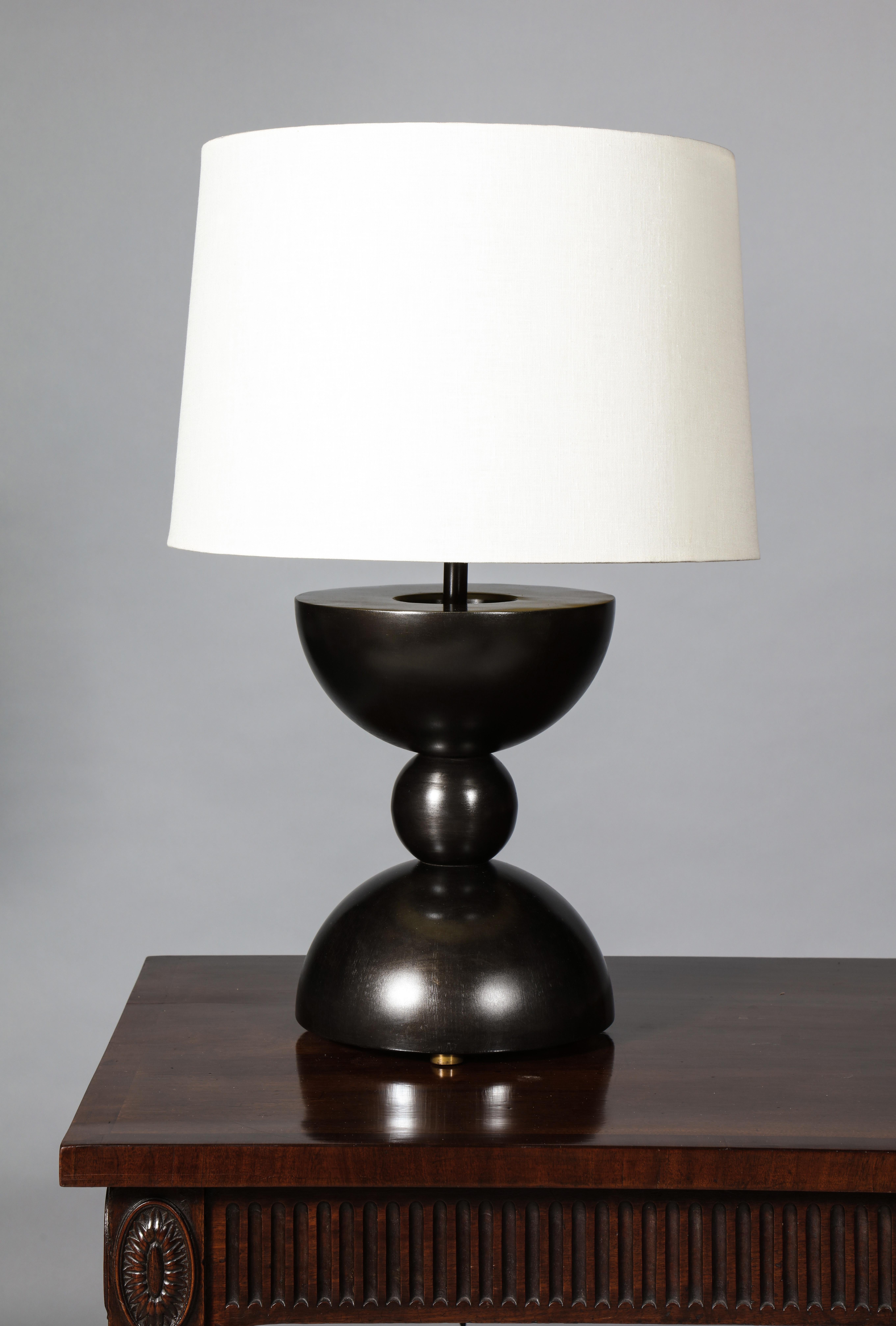 A table lamp with closed hemispherical forms cojoined by a smaller sphere. The lamp is inspired by the works of Constantin Brancusi's heavily reductive sculpture which emerged in the early/mid 20th century.

The brass detailing has been lightly