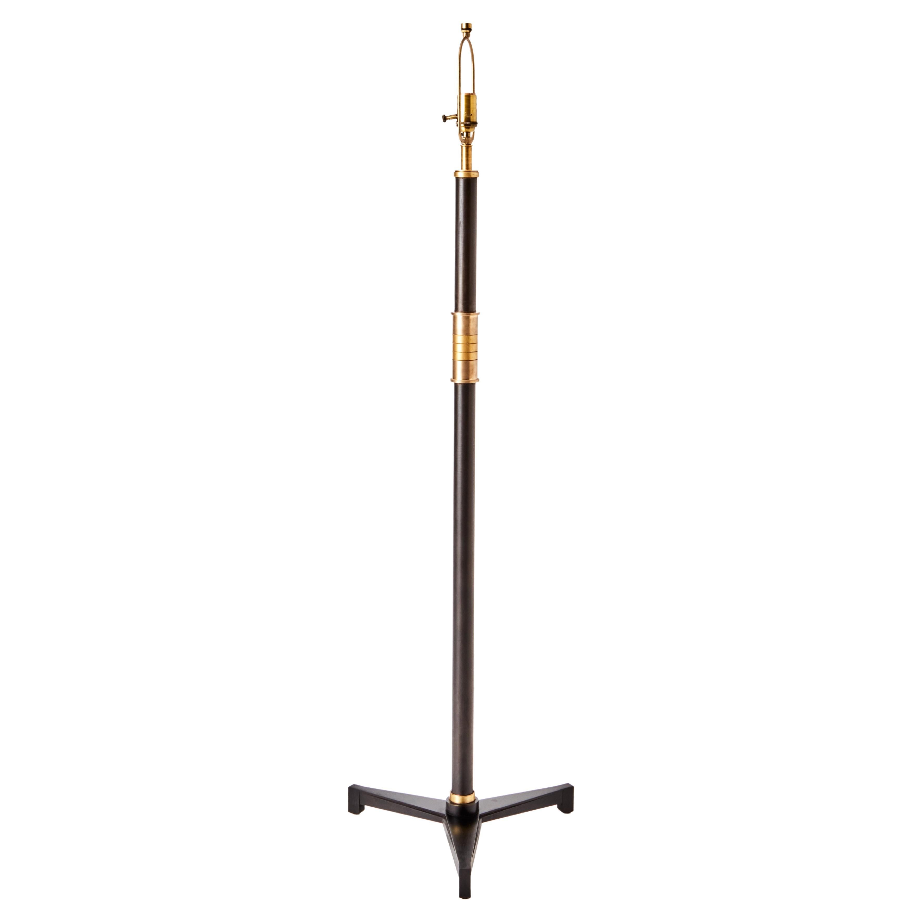 A reduced-height floor lamp intended for use as a reading lamp. Set on a tri foot base featuring tapered fluting which resonates in the art deco movement. The hilt is realized in a series of subtly contrasting brass and bronze bands. This design is