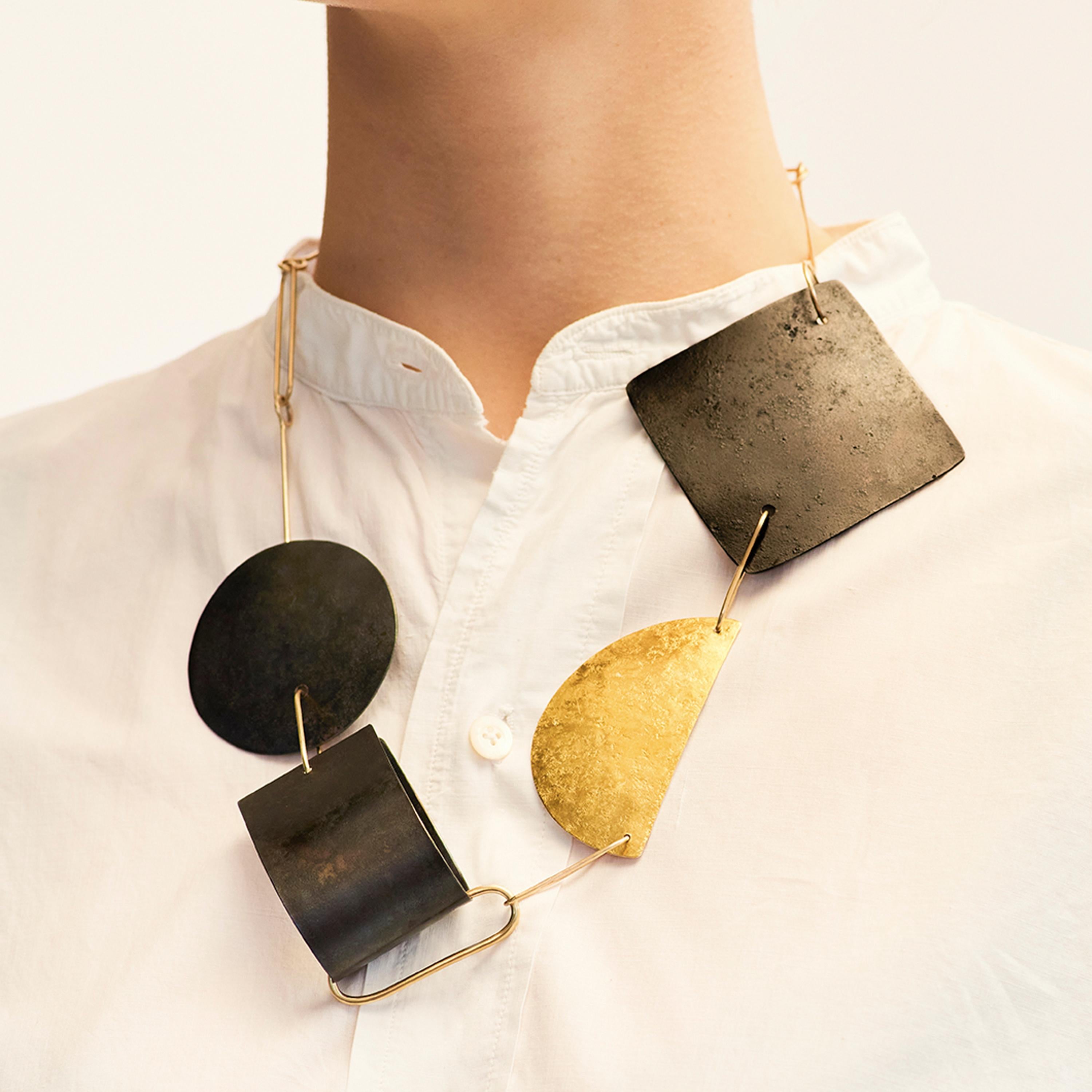 Catherine Le Gal brings together simple forms and combines materials to create her Shapes Necklace. Catherine has hammered the surface of some elements, whilst others are smooth. Three simple black forms created from patinated steel, contrast
