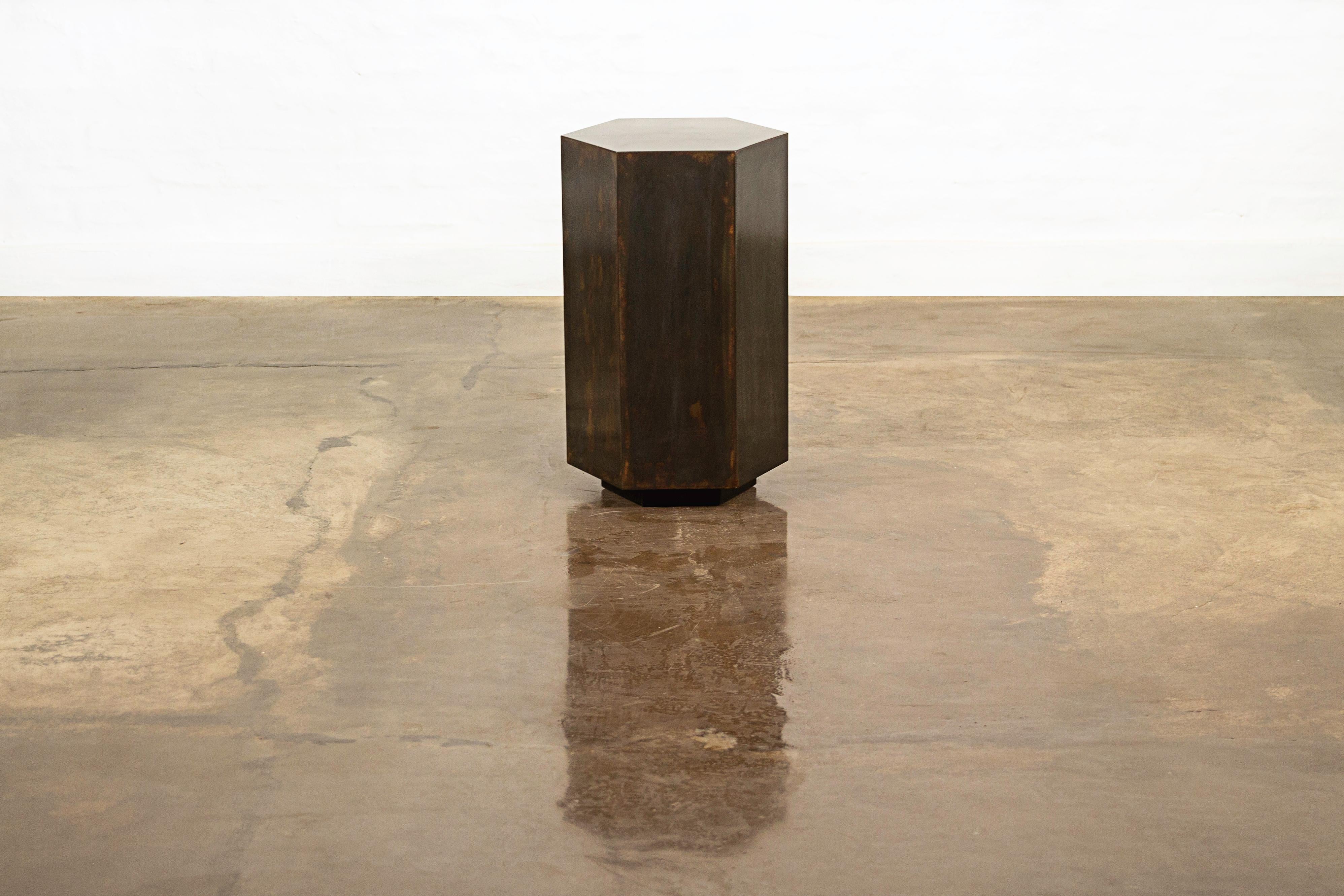 Ettore Hex's name comes from its hexagonal shape and can be specified in any of Costantini’s available materials and finishes. Shown here in patinated steel, this side table feature a modern, geometric shape that allows the subtle variations of the