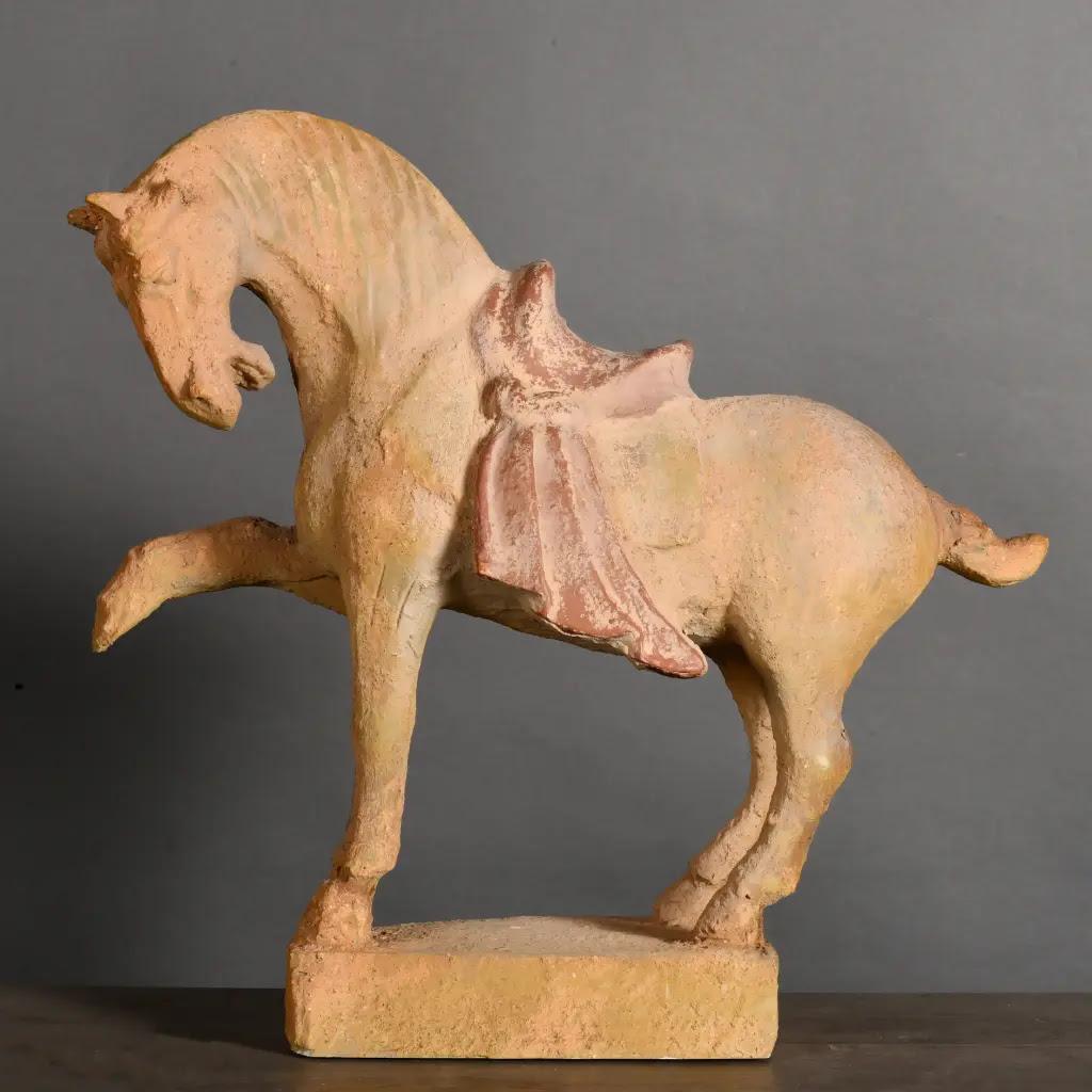 Ce cheval Tang en terre cuite patinée est une sculpture décorative raffinée inspirée de l'époque impériale chinoise. Fabriquée selon des techniques traditionnelles et finie avec une patine de pigment naturel, elle rend hommage aux figures équestres