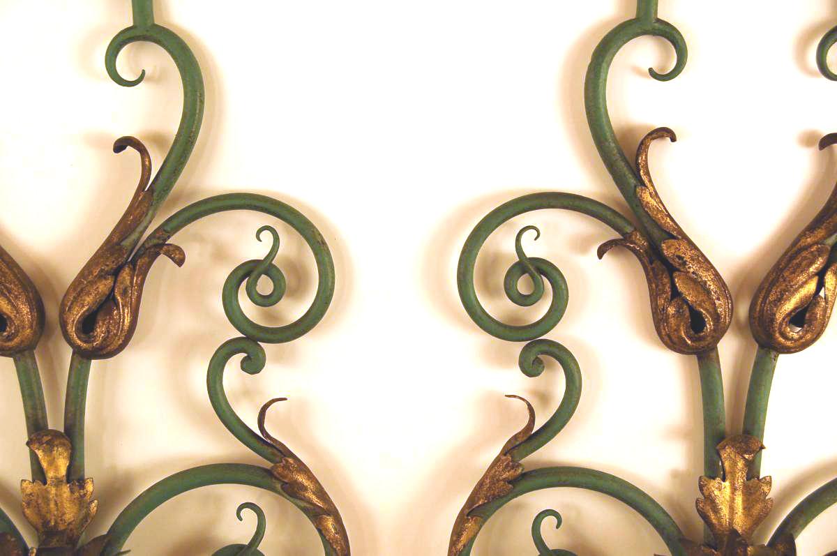 - Large pair of 1940s wall lamps
- In the style of Gilbert Poillerat
- Wrought iron with a nuanced green patina
- Decorated with windings and foliage in gilded iron on the leaf
- Hemispherical horizontal plate with flared sleeve cover in points
-