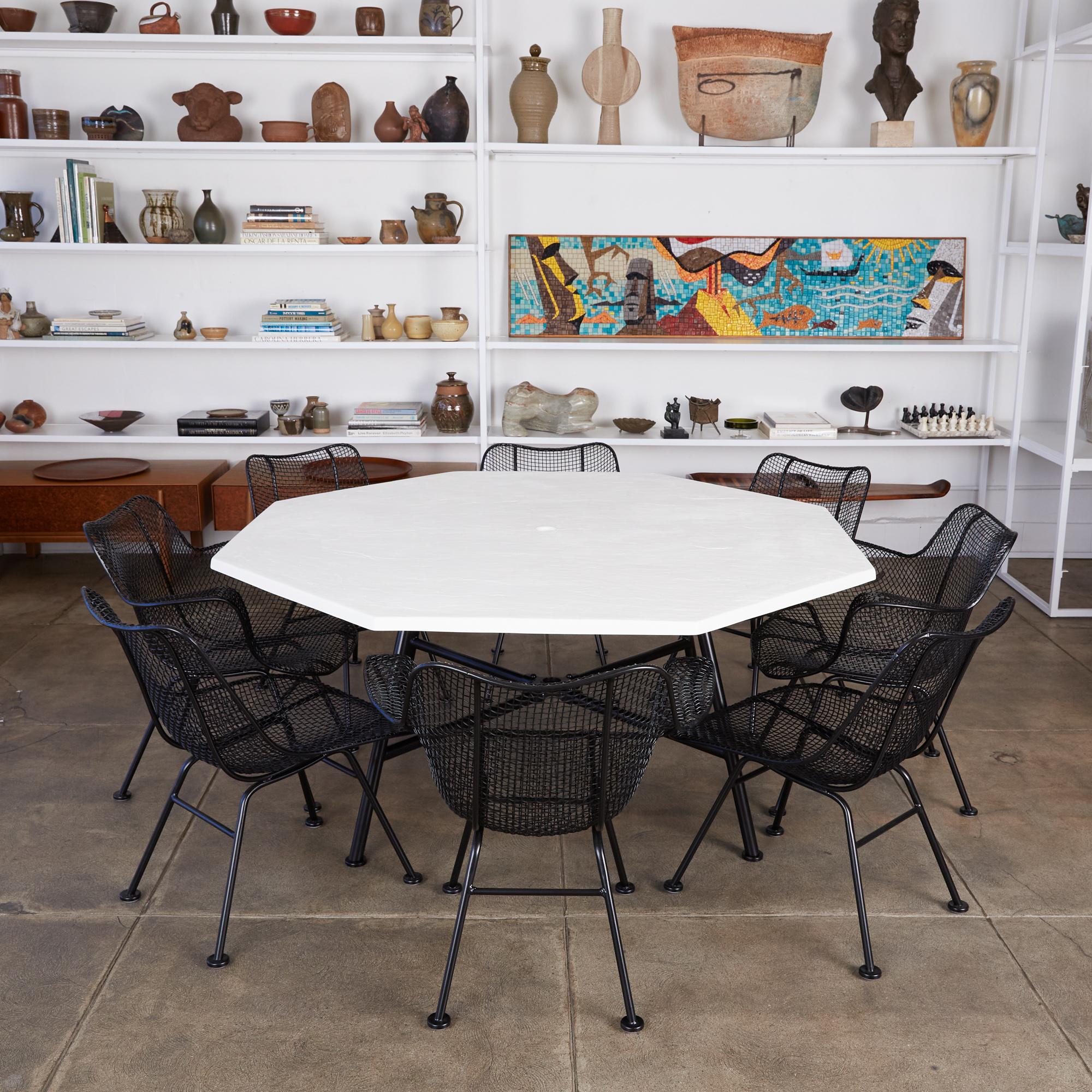 Outdoor dining set by Russell Woodard for Woodard Furniture, circa 1950s. The set features four side chairs and four armchairs from Woodard’s “Sculptura” line designed in 1956. Each chair has a molded mesh frame that sits atop four wrought iron legs