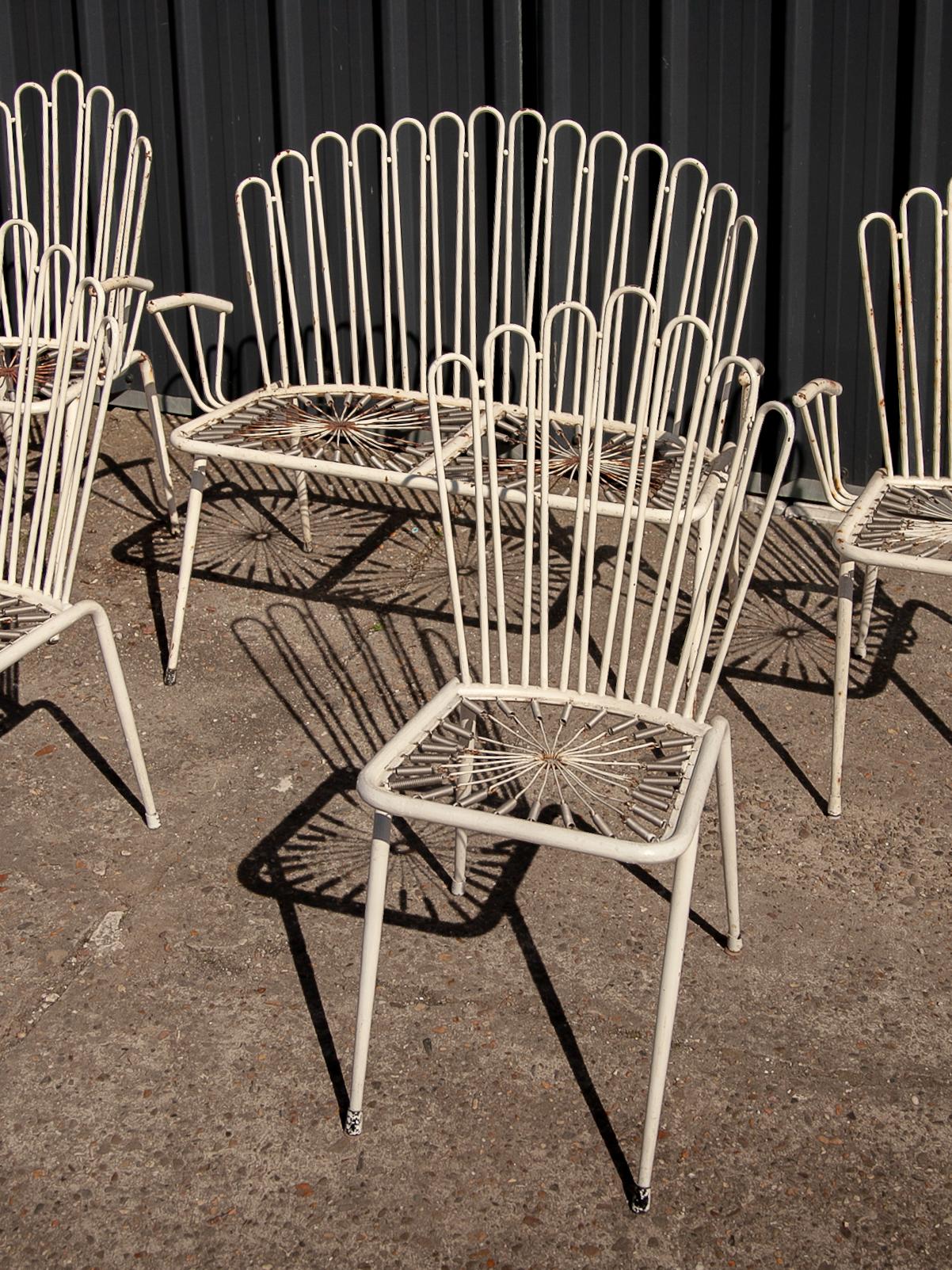 Midcentury wrought iron metal outdoor patio set featured four chairs and one two-seater a loveseat designed in style of the French designer Mathieu Matégot. White enameled wire frame and armrests, frames in original condition with visible wear of