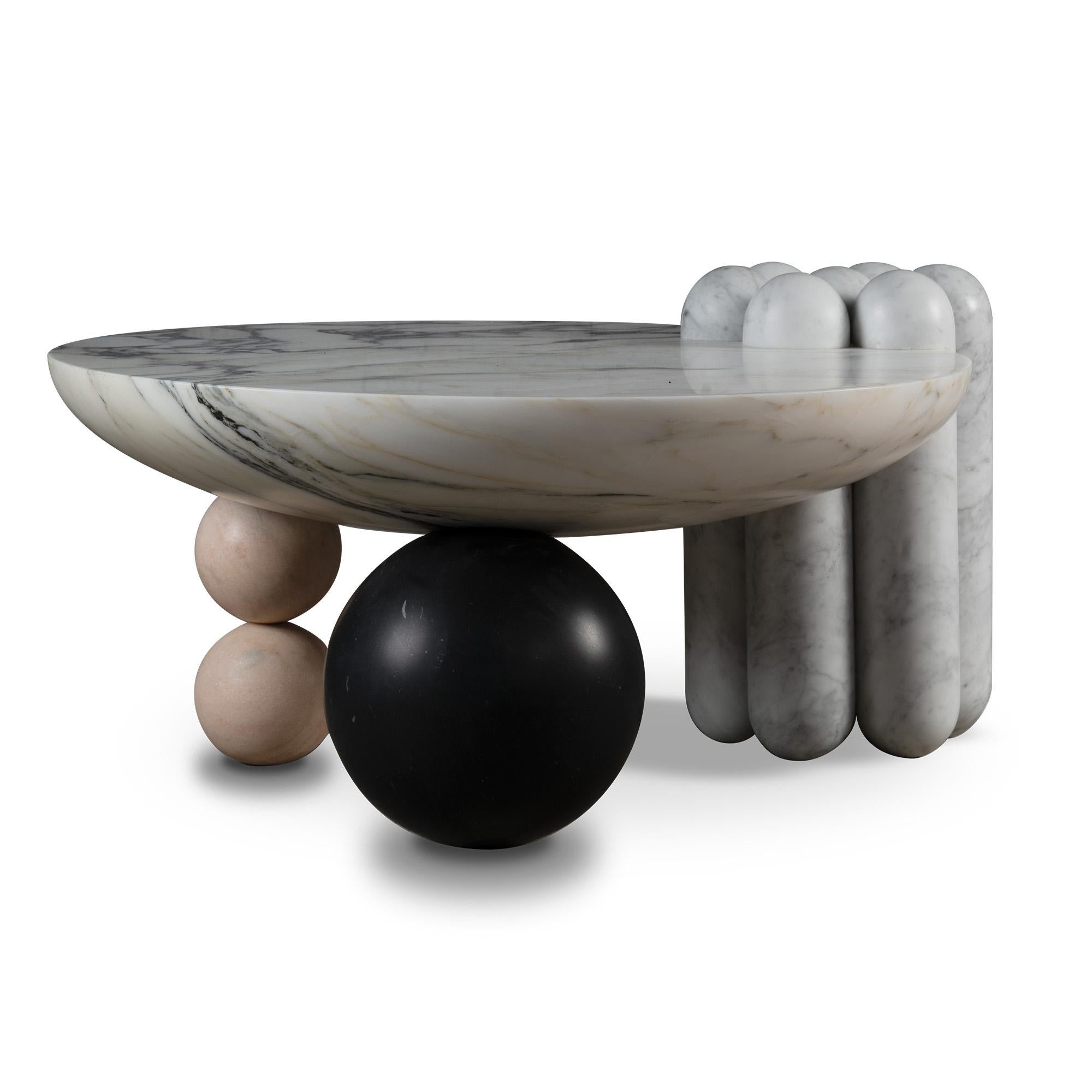 La table basse en marbre Patisserie est un ensemble de différentes formes inspirées de la pâtisserie - un pied latéral en forme de canelé et deux pieds en forme de bonbon soulèvent un plateau en forme de coupe pour un assemblage agréablement