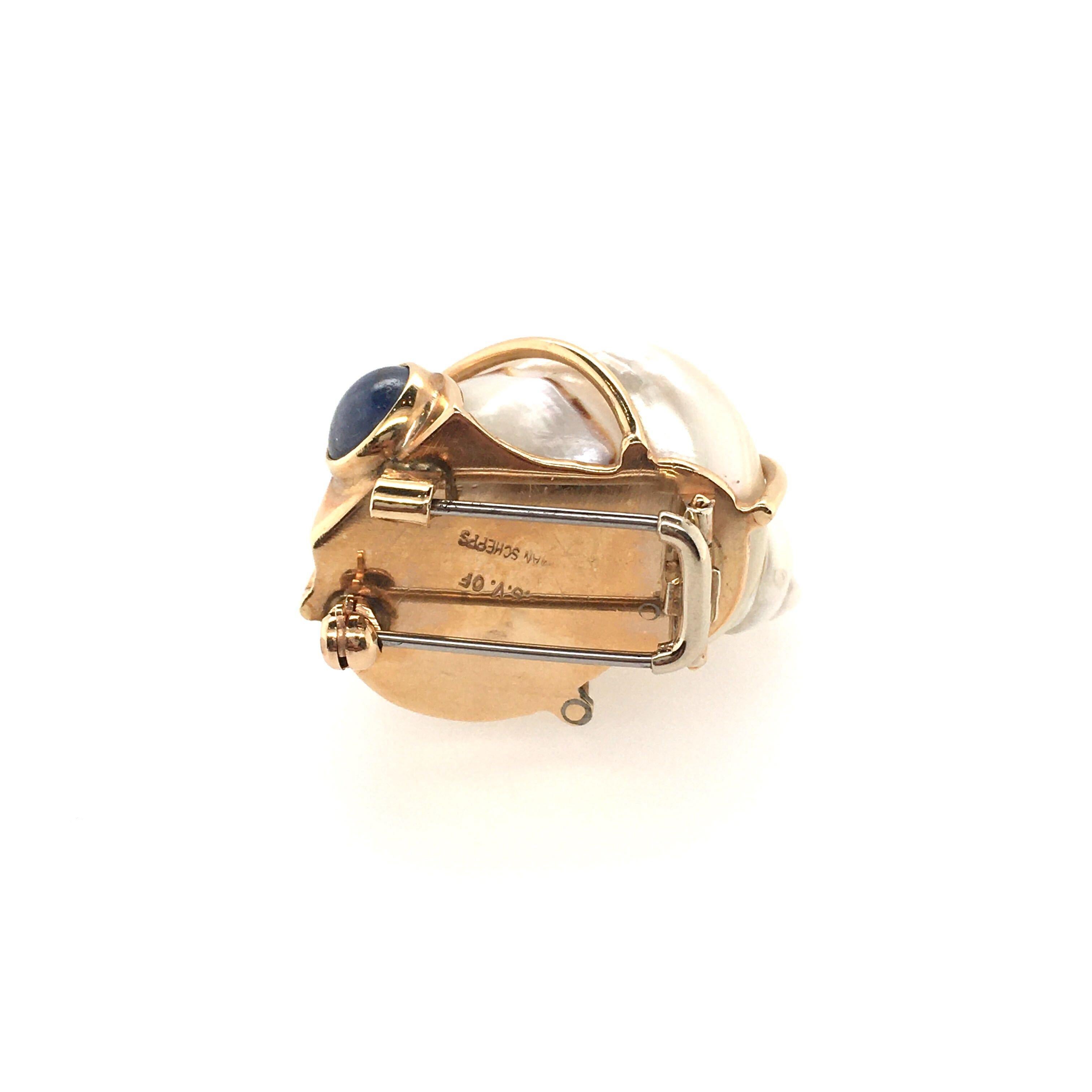 A 14 karat yellow gold , turbo shell and sapphire brooch. Patricia Schepps Vail for Seaman Schepps. Circa 1975. Set with a white turbo shell, wrapped in yellow gold wire, enhanced at each end by a cabochon sapphire. Length is approximately 1 1/4