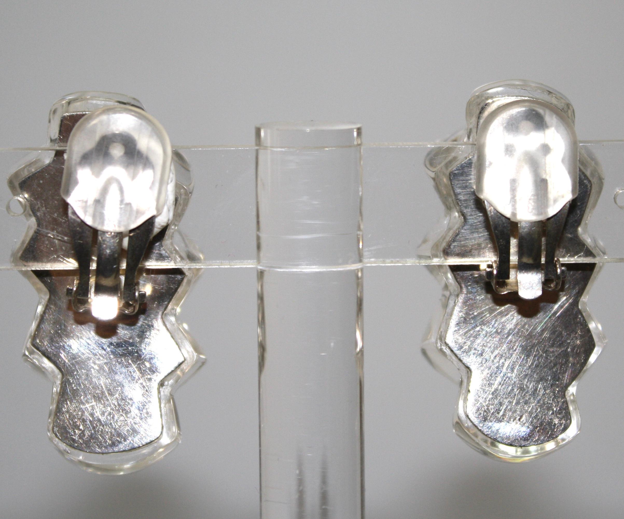 Sterling silver back gives a beautiful reflection of light to these lucite clip earrings. Signature on the back.