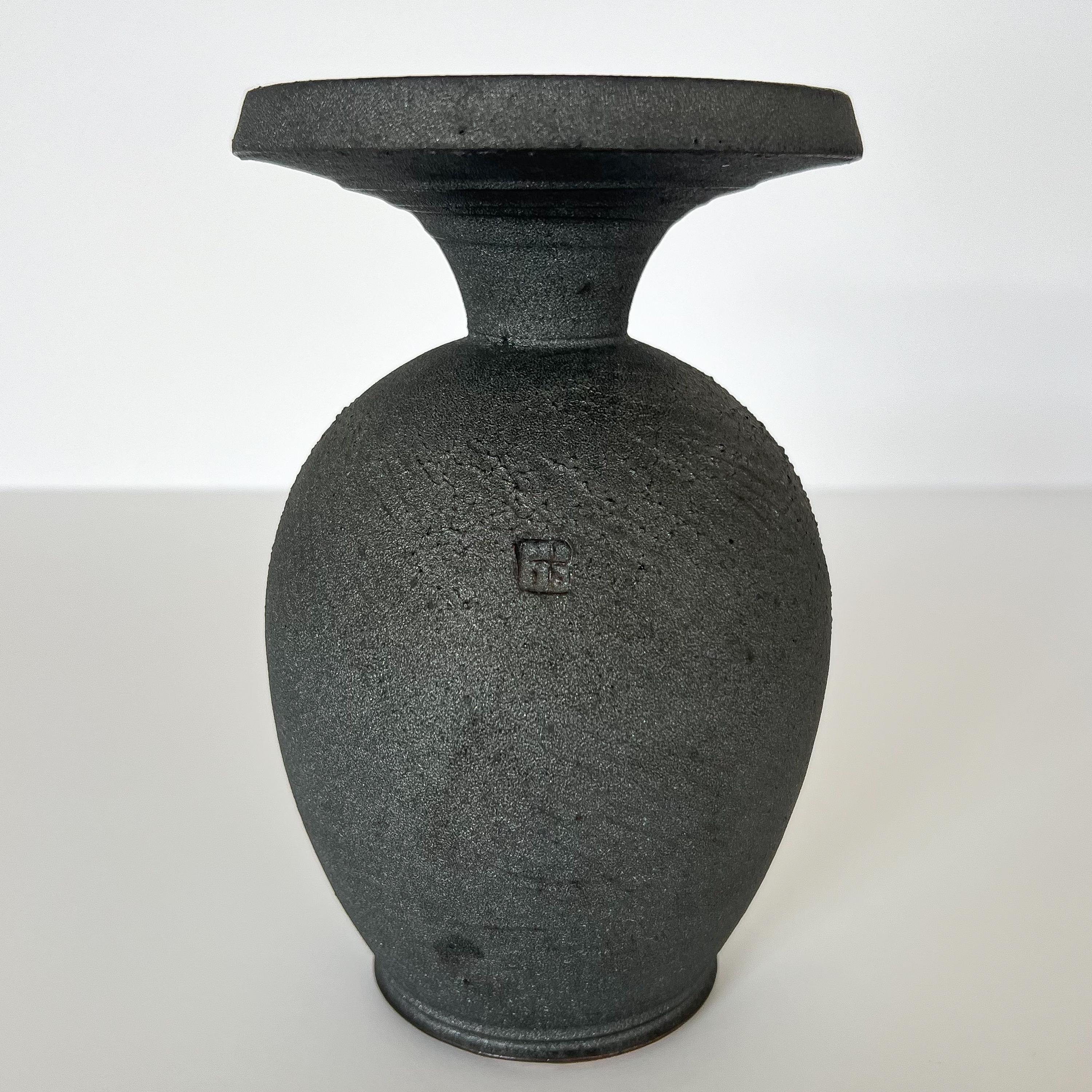 A modern glazed stoneware pottery vase by Patrick Horsley, USA circa 2000s. A hand thrown stoneware vase with black diamond glazed body and a blue an purple glazed rim. Measures 8