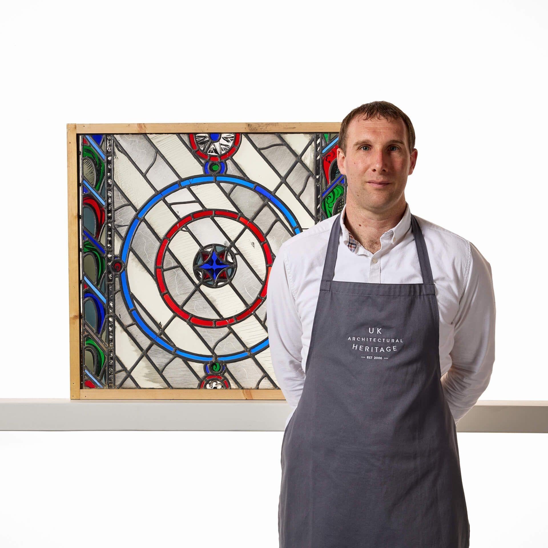 Una vidriera emplomada contemporánea del taller de Patrick Reyntiens (1925-2021). Atribuido al artista, este panel de vidrieras representa un vibrante diseño detallado con círculos en rojo y azul entre coloridos paneles verticales a ambos lados. Es
