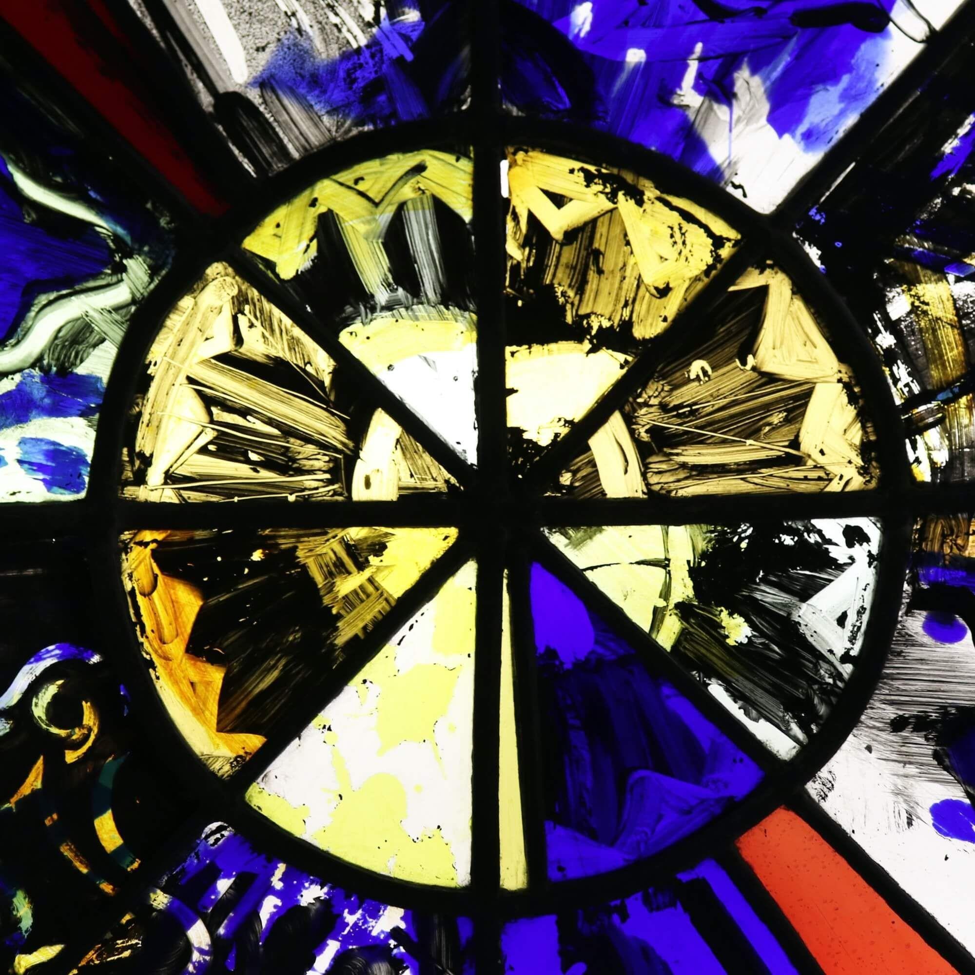 A modern stained glass window from the studio of Patrick Reyntiens (1925-2021). Attributed to the artist, this stained glass panel depicts a sunburst-type design with abstract hand-painted details including what appears to be a fish to the lower