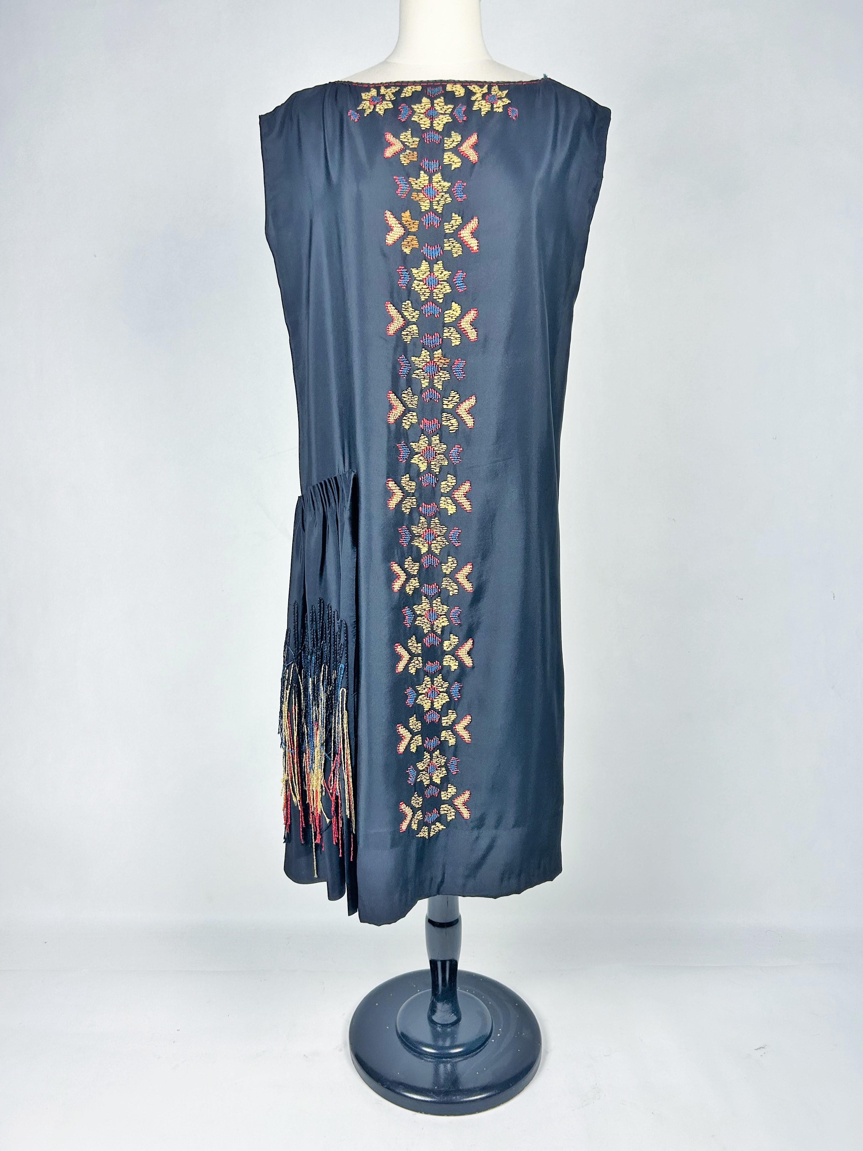 CIRCA 1918-1922. Frankreich
Patriotisches französisches Abendkleid aus besticktem schwarzem Seidenkrepp aus dem Ende des Ersten Weltkriegs. Inspiriert von den grafischen Entwürfen der Ballets Russes und den Kreationen von Jeanne Lanvin, ist dieses