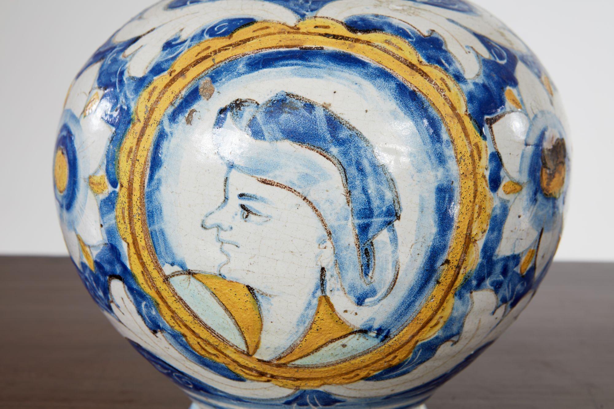Rare jarre à drogue italienne de la fin du XVIe siècle, de forme cylindrique, à décor polychrome en bleu et jaune sur fond blanc, avec le portrait du patron de la ville coiffé d'un chapeau de fantaisie au milieu de feuilles d'acanthe et de fleurs