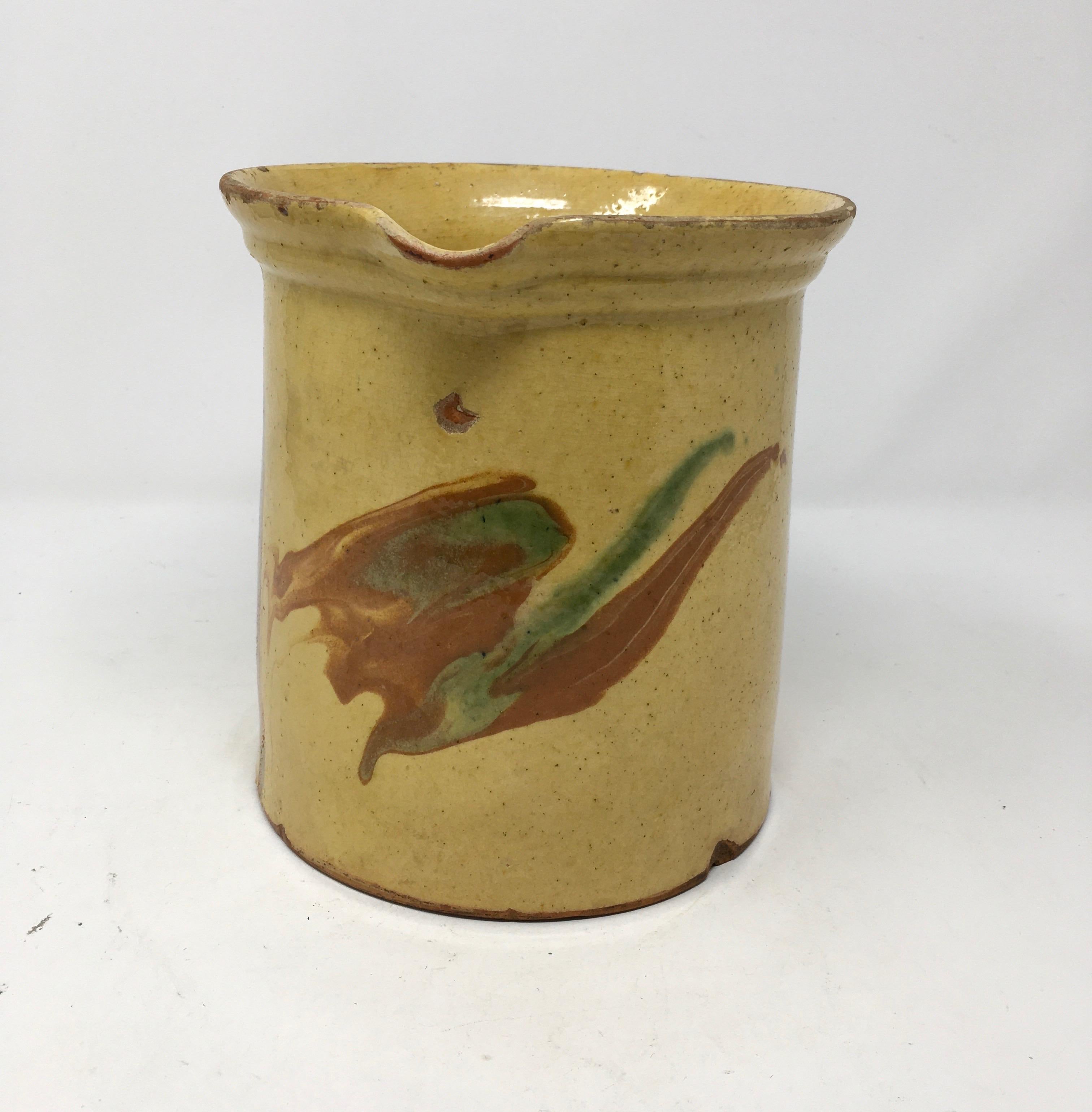 This colorful pitcher has has a wide mouth and a small spout. It is decorated with green and terracotta color glazed swatches. It would also be lovely filled with flowers. It is in good condition with some small chips around the mouth and