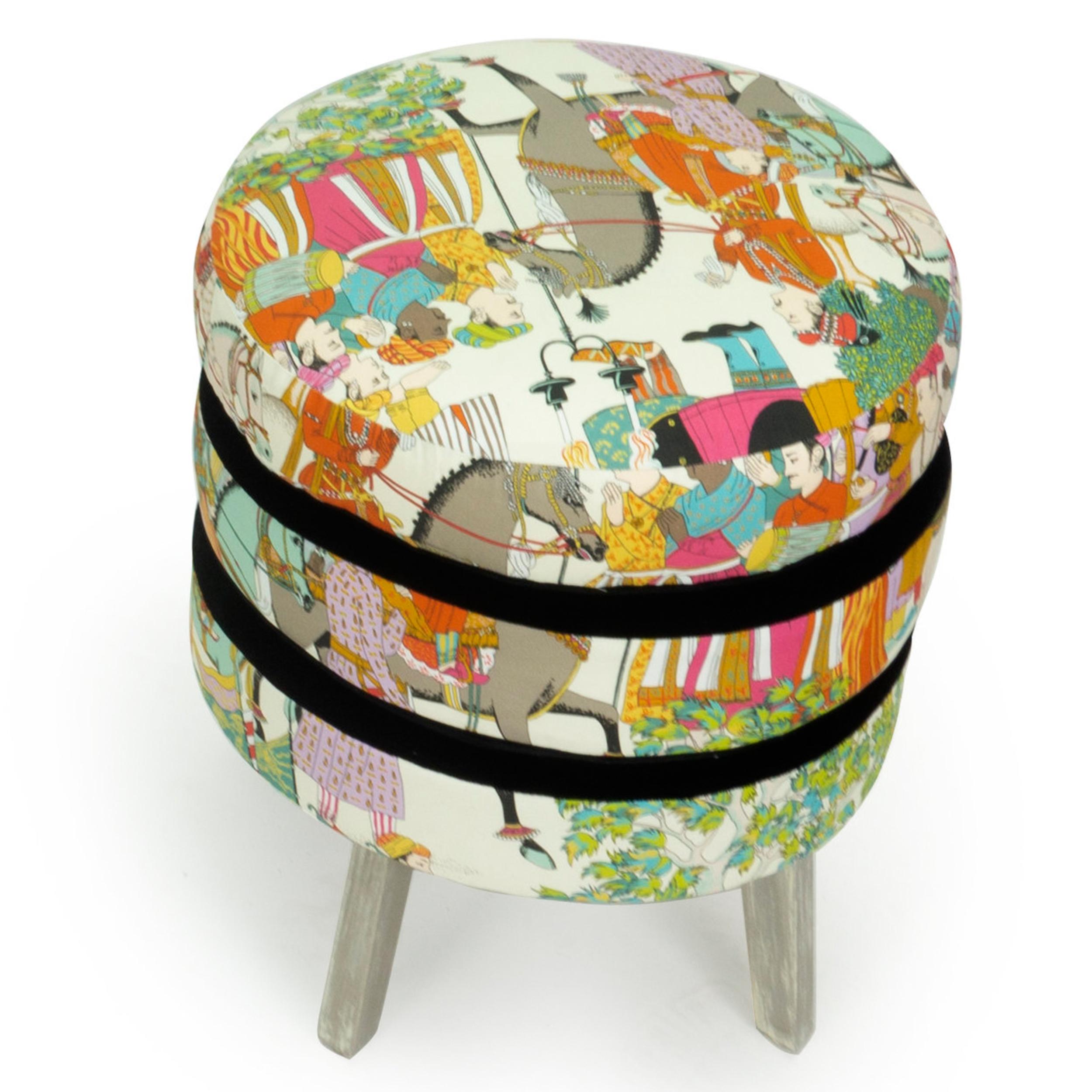Our three layered ottoman stool features three layers of soft foam cushioning upholstered with an exotic toile fabric by Manuel Canovas with black velvet outlining. The legs are maple wood with a hand brushed painted finish. This piece can be made