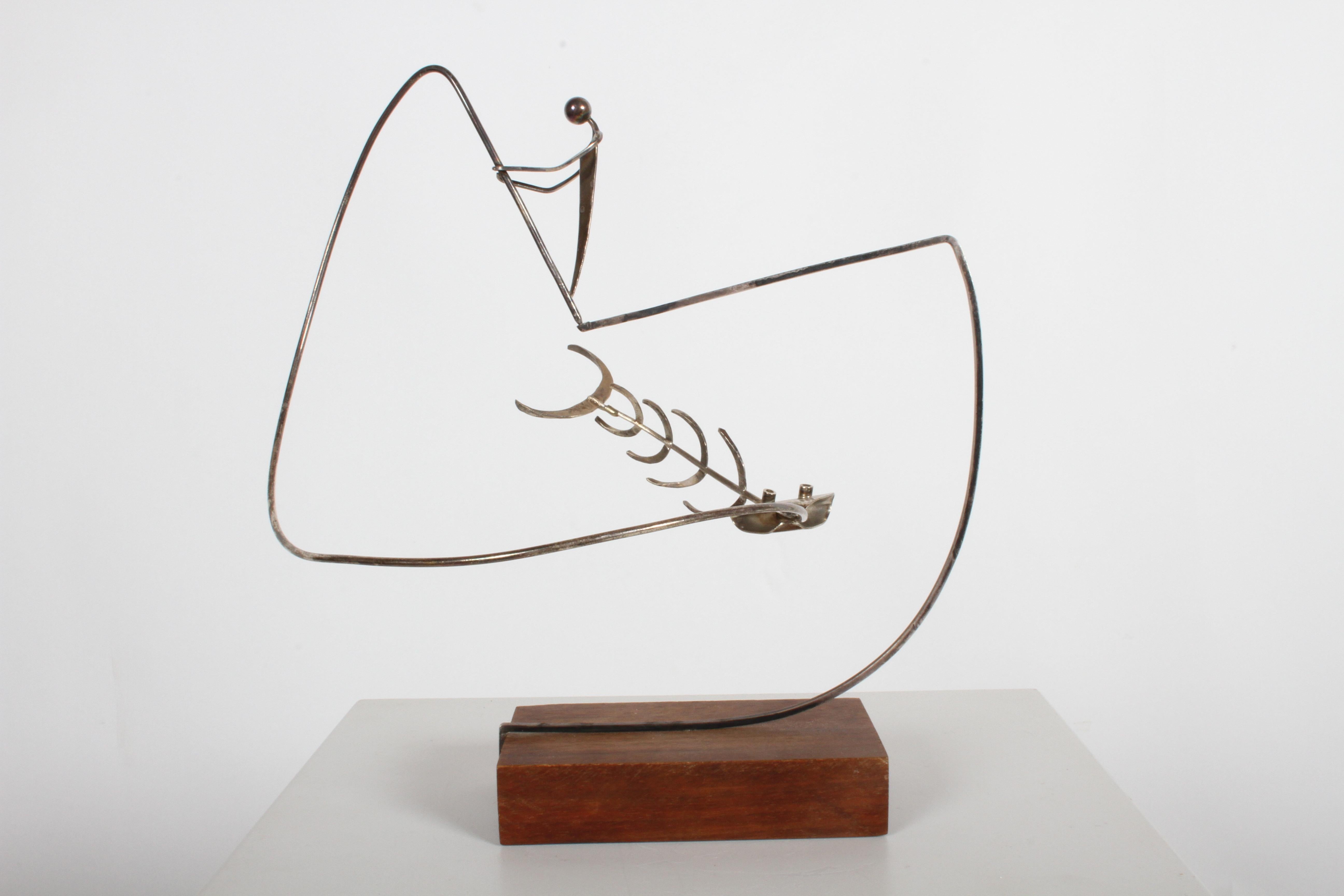 Paul A. Lobel (1899-1983) modernist silversmith, sculptor and artist. Lobel sold his jewelry and art at his Greenwich village shop in the 1940s and 1950s. This two-piece sterling Kinetic sculpture is of a fisherman catching a fish on a wood base.