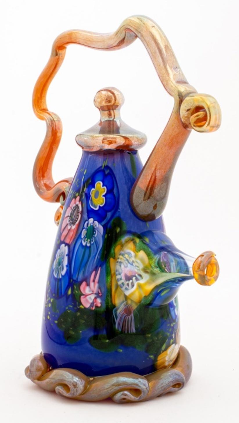 Paul Allen Counts (American, XX-XXI) studio art glass sculpture in the form of an oblong Surrealist teapot, the handle and borders in iridescent gold-tone glass, the body of blue glass with polychrome millefiori flowers, signed 