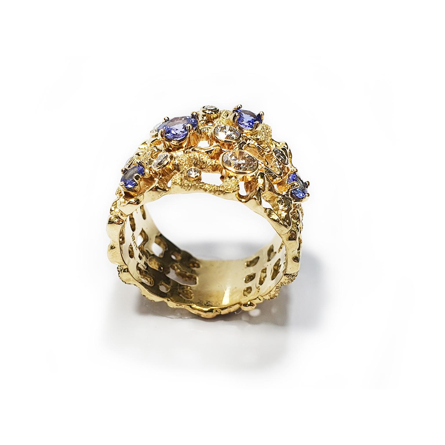 Paul Amey’s Tanzanite dress ring was created from 18K yellow gold and features 4 blue Tanzanite’s (a 21pt, 11pt, two 5pt) that are claw set. Highlighting the Tanzanite stones are 8 round white diamonds (a 15pt, two 8pt, two 3pt) that are chenier