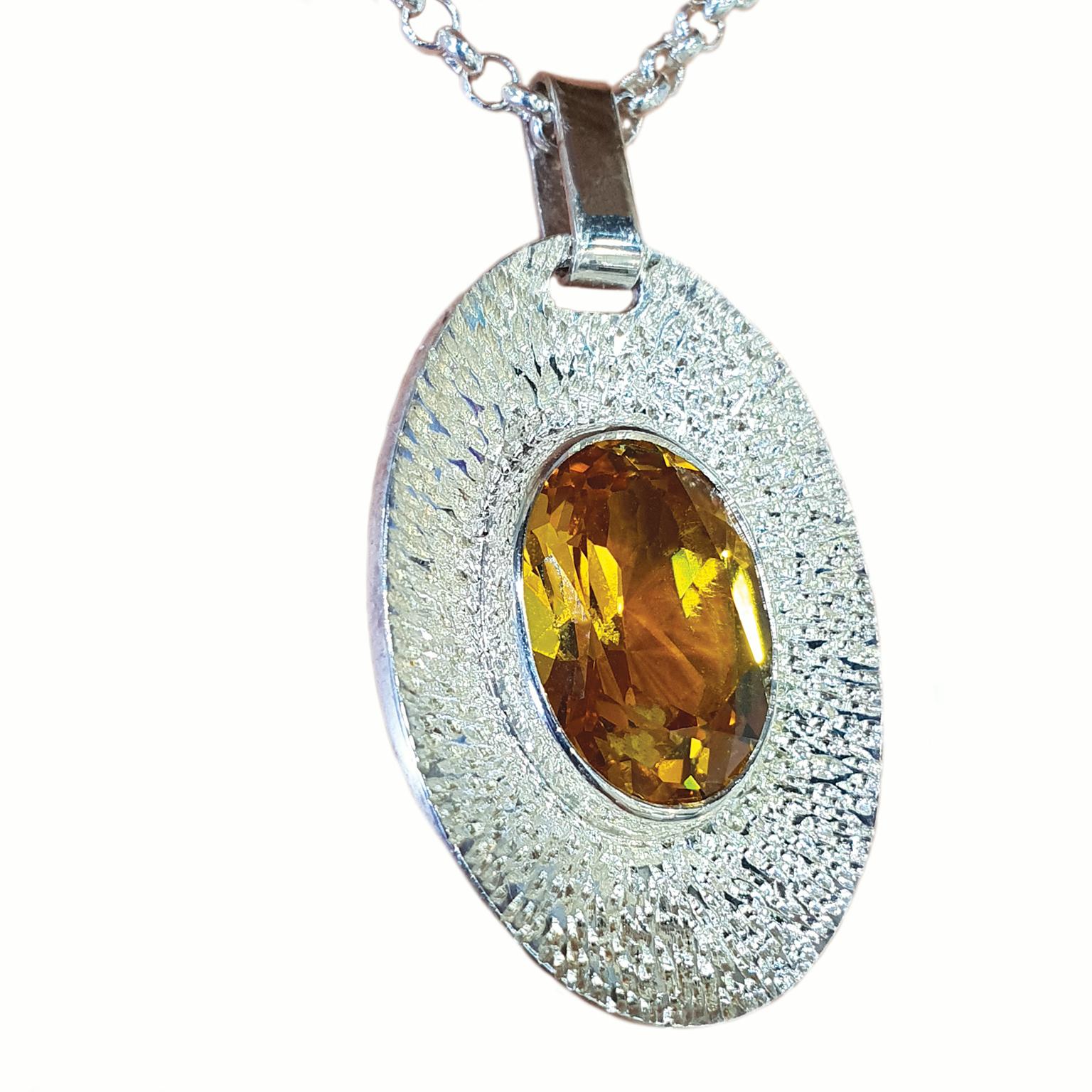 Paul Amey’s yellow oval pendant was crafted from tarnish resistant Sterling Silver. The pendant features a golden yellow synthetic corundum stone surrounded by a textured background. The pendant weighs 6.2 grams and measures 27mm by 19mm.

The