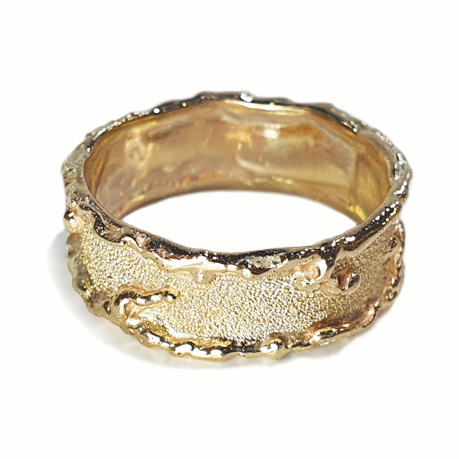 Der Ring Gold Molten Edge von Paul Amey wurde in Handarbeit aus 9 K Gelbgold hergestellt. Der Ring hat ein 7 mm breites Band, geschmolzene Tropfen und ist mit der für Paul Amey typischen Textur versehen. Der Ring wiegt 3,6 Gramm und hat derzeit die