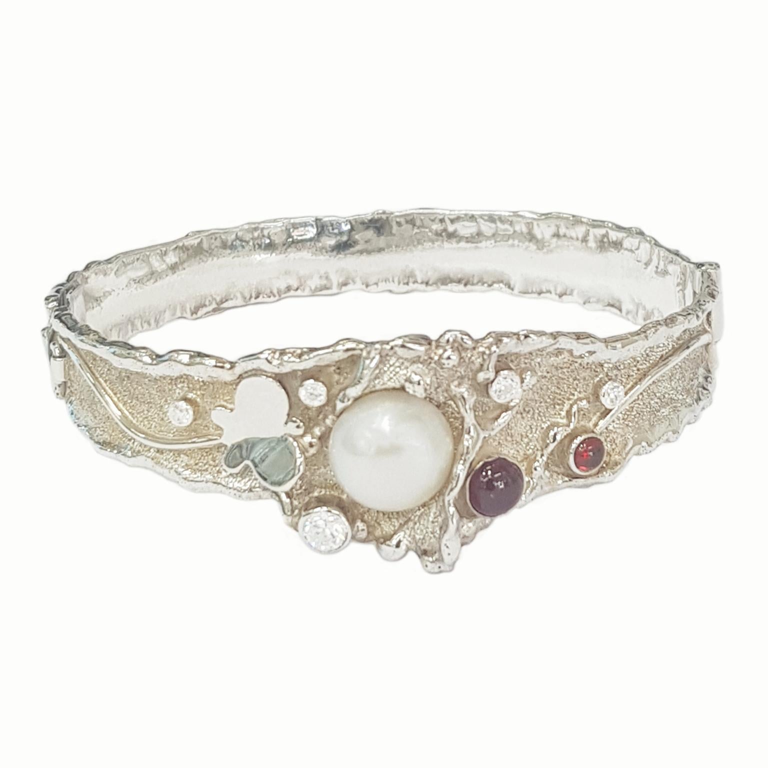 Paul Amey’s signature molten edge bangle is a totally unique and completely handcrafted and created by Paul Amey.  This garnet and pearl bangle was crafted from Sterling Silver with the centre width of the bangle approximately 20mm and then tapering