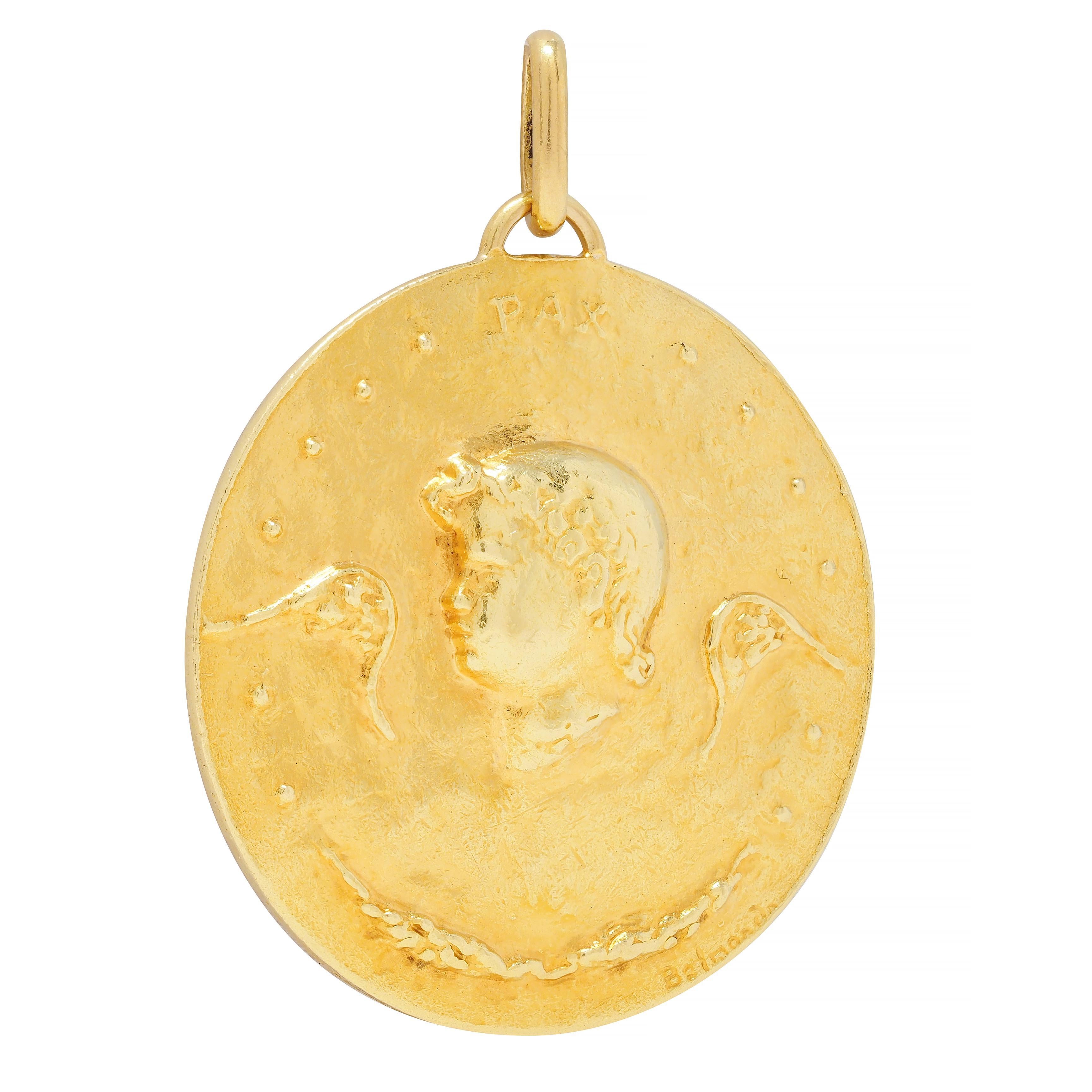 Designed as a round gold disk double-sided with raised cameos
One side depicts a cherub head flanked by wings with laurel
Inscribed 'PAX' translating from French as 