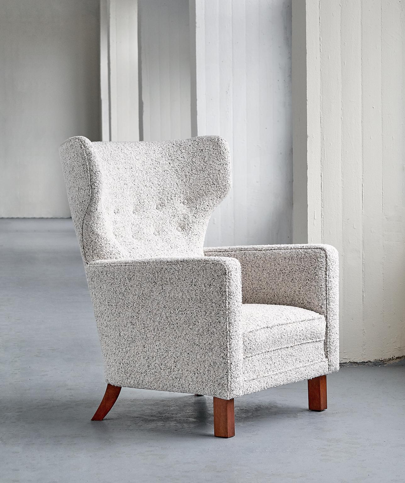 Ce fauteuil rare a été conçu par Paul Boman et produit par sa société Oy Paul Boman AB en Finlande dans les années 1940. Le design offre un beau contraste entre les lignes courbes du haut dossier ailé et les lignes droites des accoudoirs. Les pieds