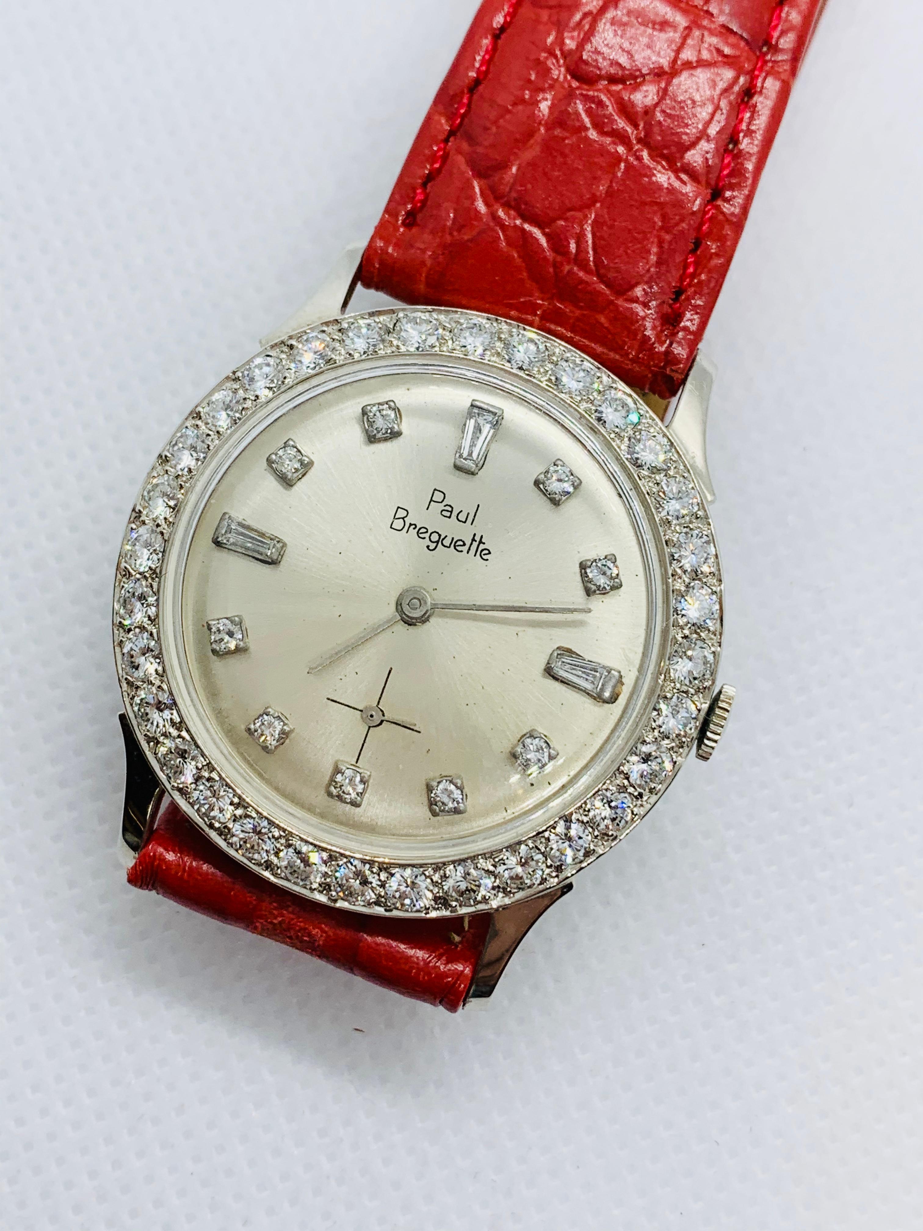 This is an absolutely stunning tuxedo watch! This estate piece is made in 14k White Gold. It is 33 mm in diameter and has a champagne colored dial with diamond markers as well as a diamond bezel. It has manual wind movement. The red leather band is