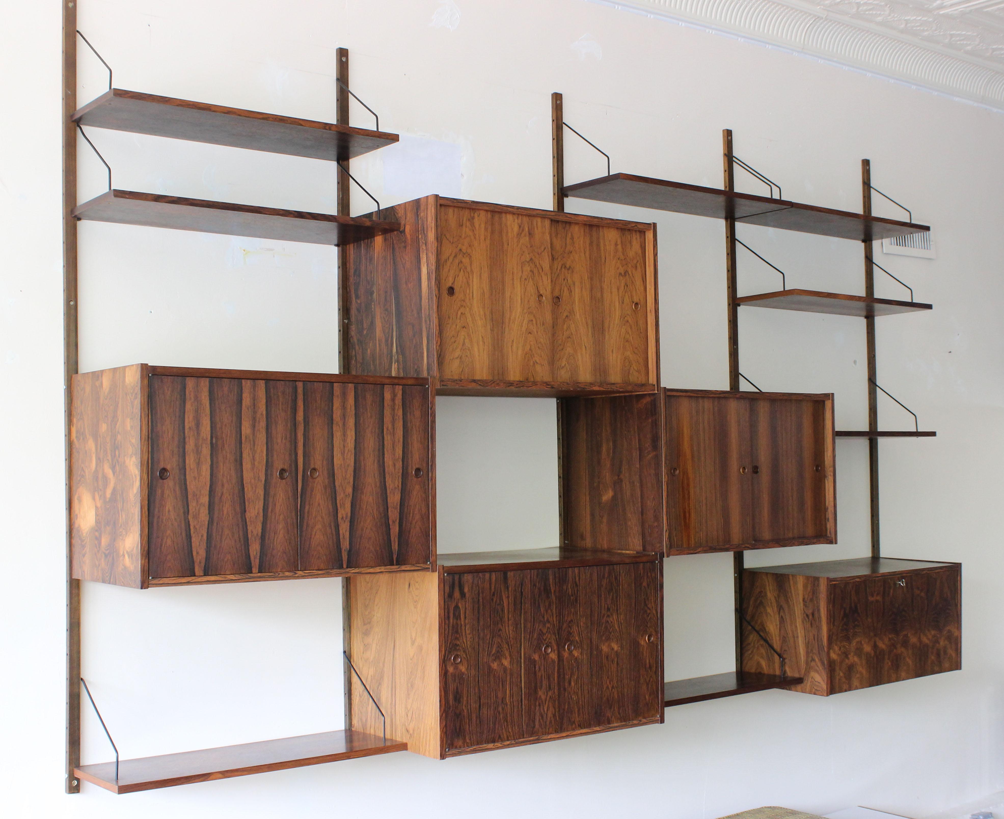 Paul Cadovious Rosewood Wall Unit.
Highly versatile and functional modular wall unit in rosewood by Danish designer Poul Cadovius. This set includes two spring-locked cabinets, two sliding door cabinets with one shelf each, and a locking desk-like