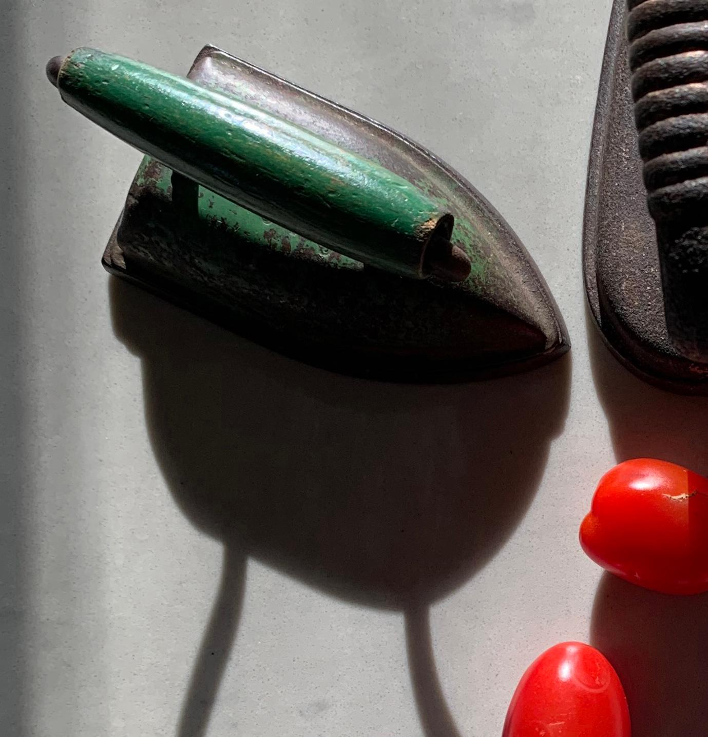 Questa è una fotografia incorniciata a pigmenti d'archivio che raffigura una natura morta astratta con ferri da stiro verde antico e pomodori prugna rosso vivo, stampata su Hahnemuhle Photo Rag 308 gsm dall'artista Paul Cava. L'attore principale del
