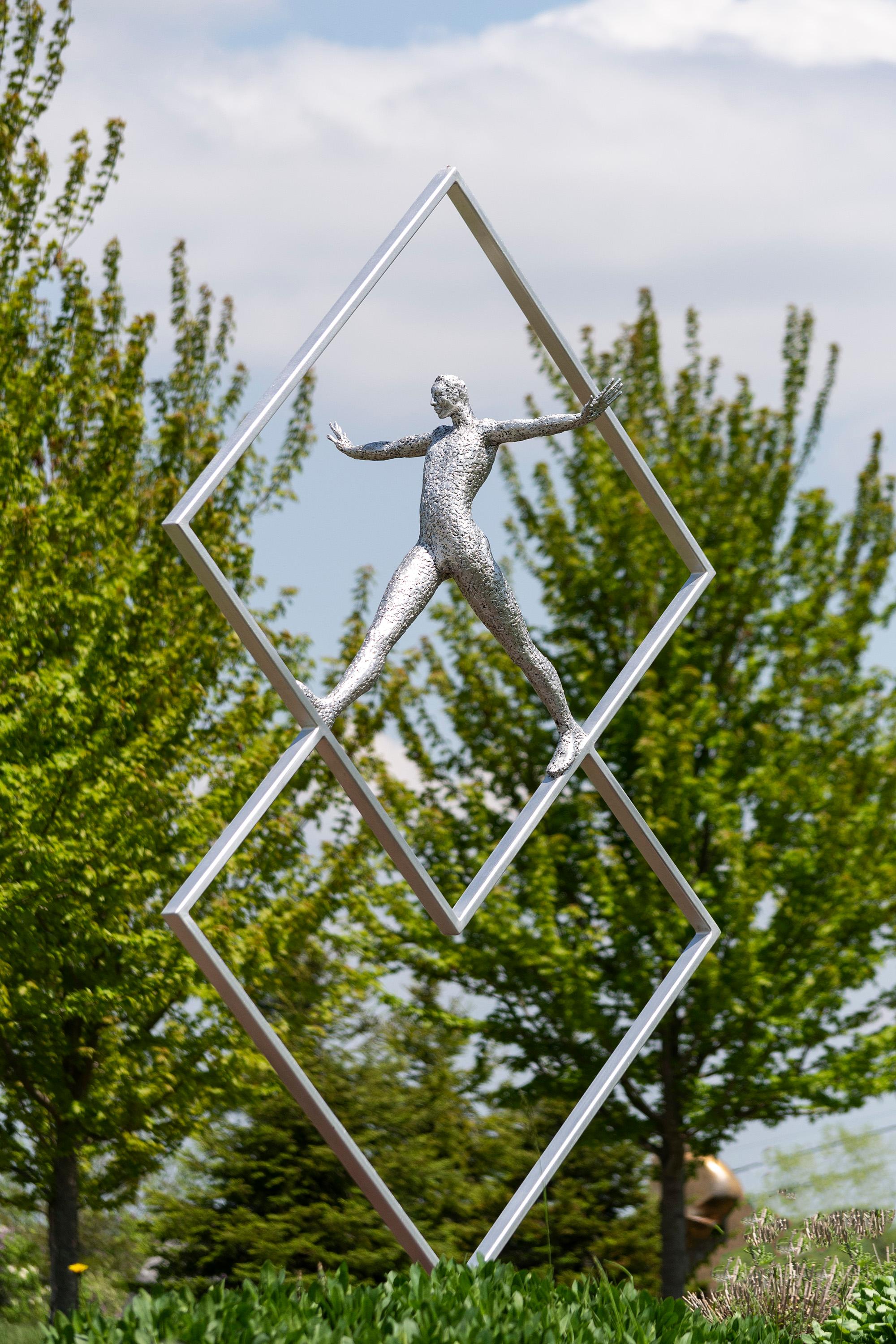 Las atractivas esculturas contemporáneas del artista quebequés Paul Duval han conseguido un público internacional. Forjadas en aluminio, las figuras de gran textura suelen adoptar una pose dramática: ésta camina dentro de dos cuadrados en ángulo. La