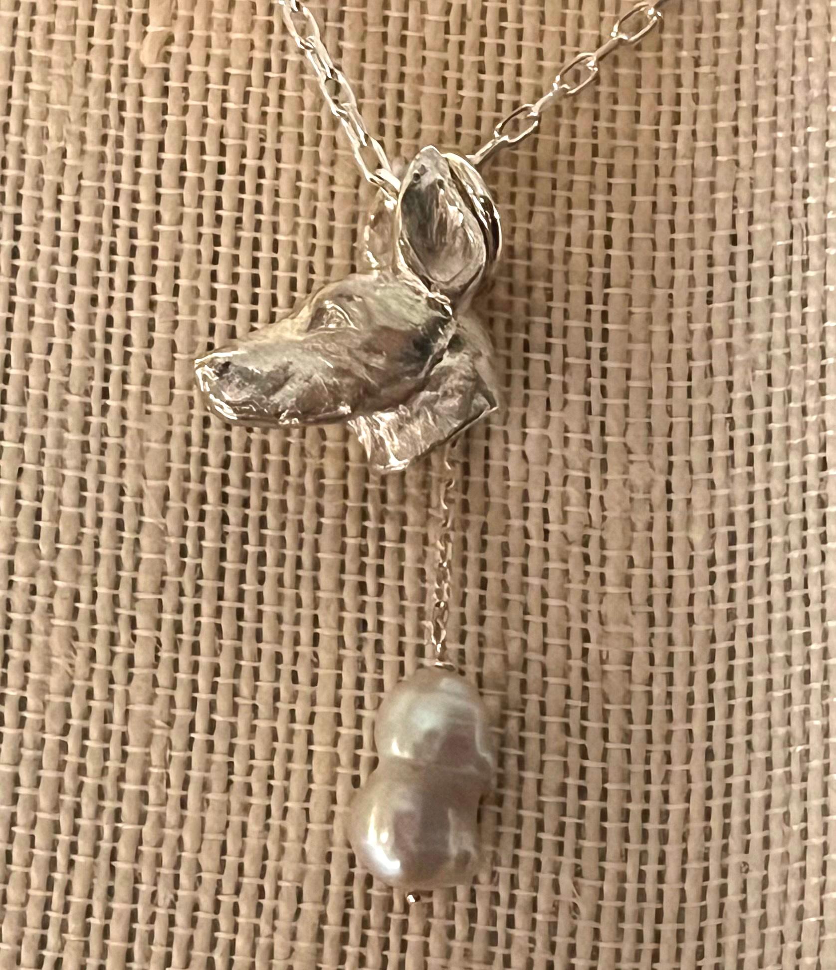     Miniature wildlife artist, Paul Eaton from England, hand sculpted a sterling silver Doberman dog head pendant which is elegantly framed with one or two drop freshwater pearls.    The bespoke Doberman dog sculpture is made into jewelry you can